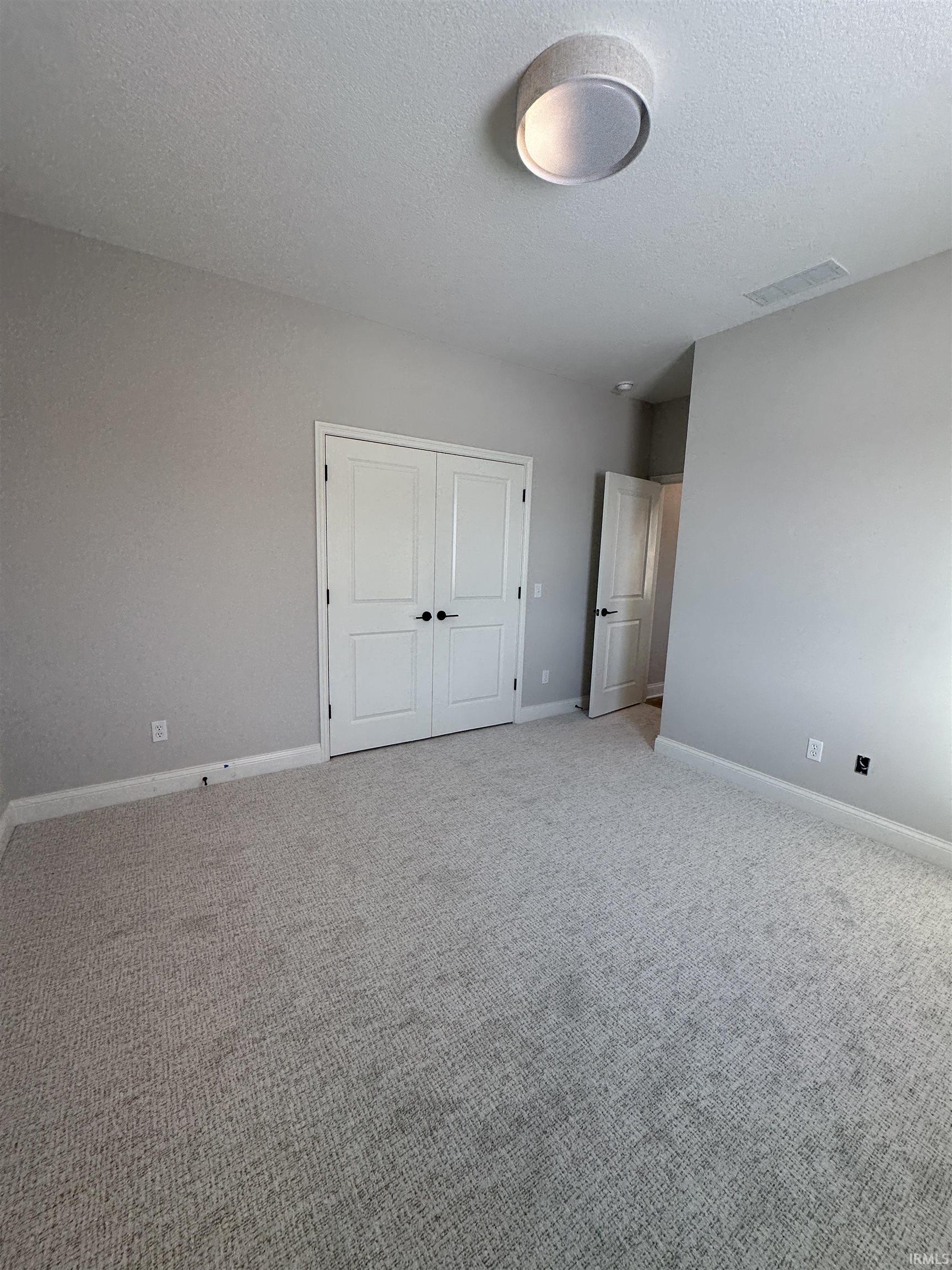 Unfurnished bedroom with a textured ceiling, a closet, and carpet floors