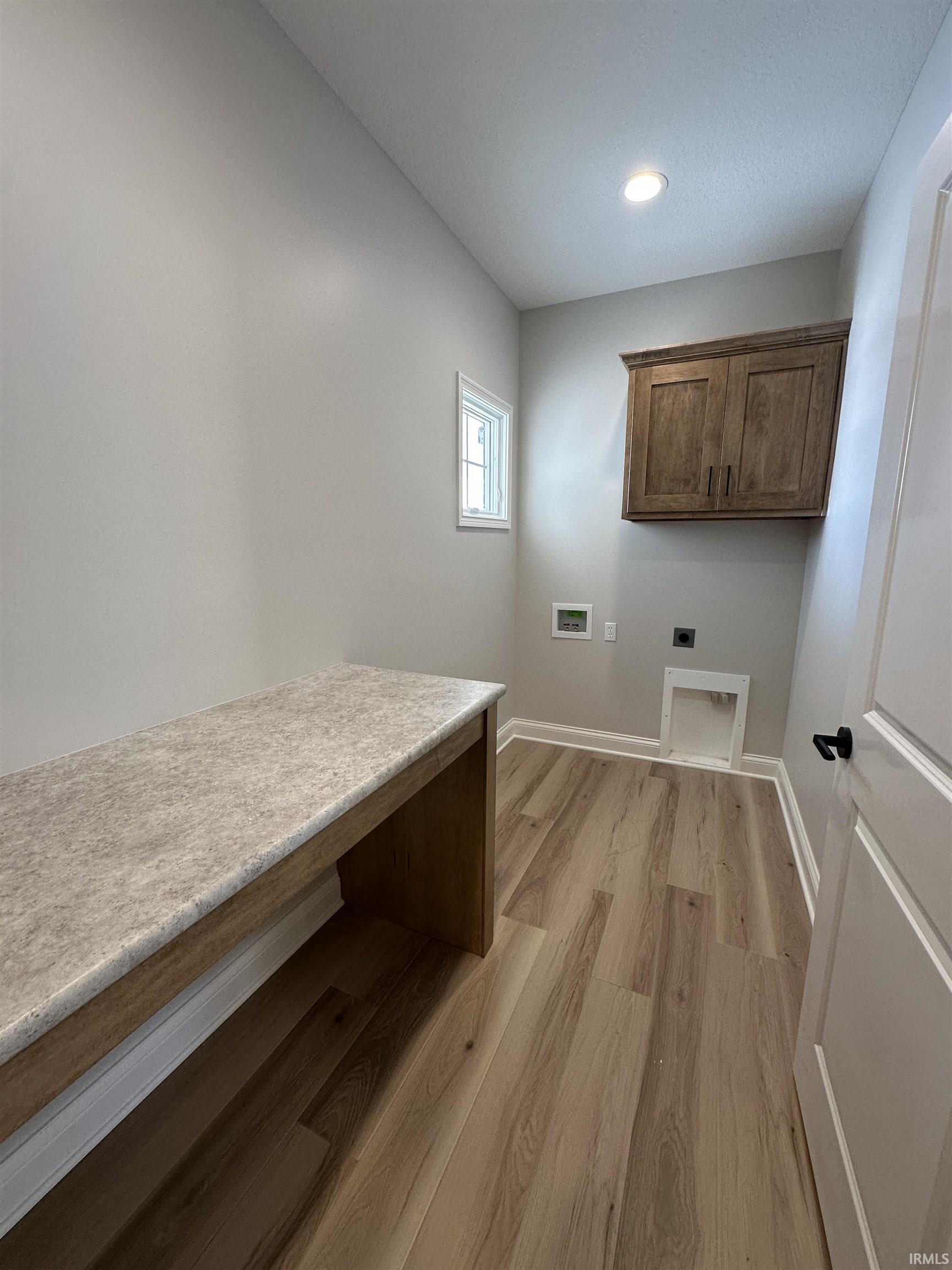 Laundry area featuring hookup for a washing machine, cabinet space, light wood-style flooring, hookup for an electric dryer, and recessed lighting