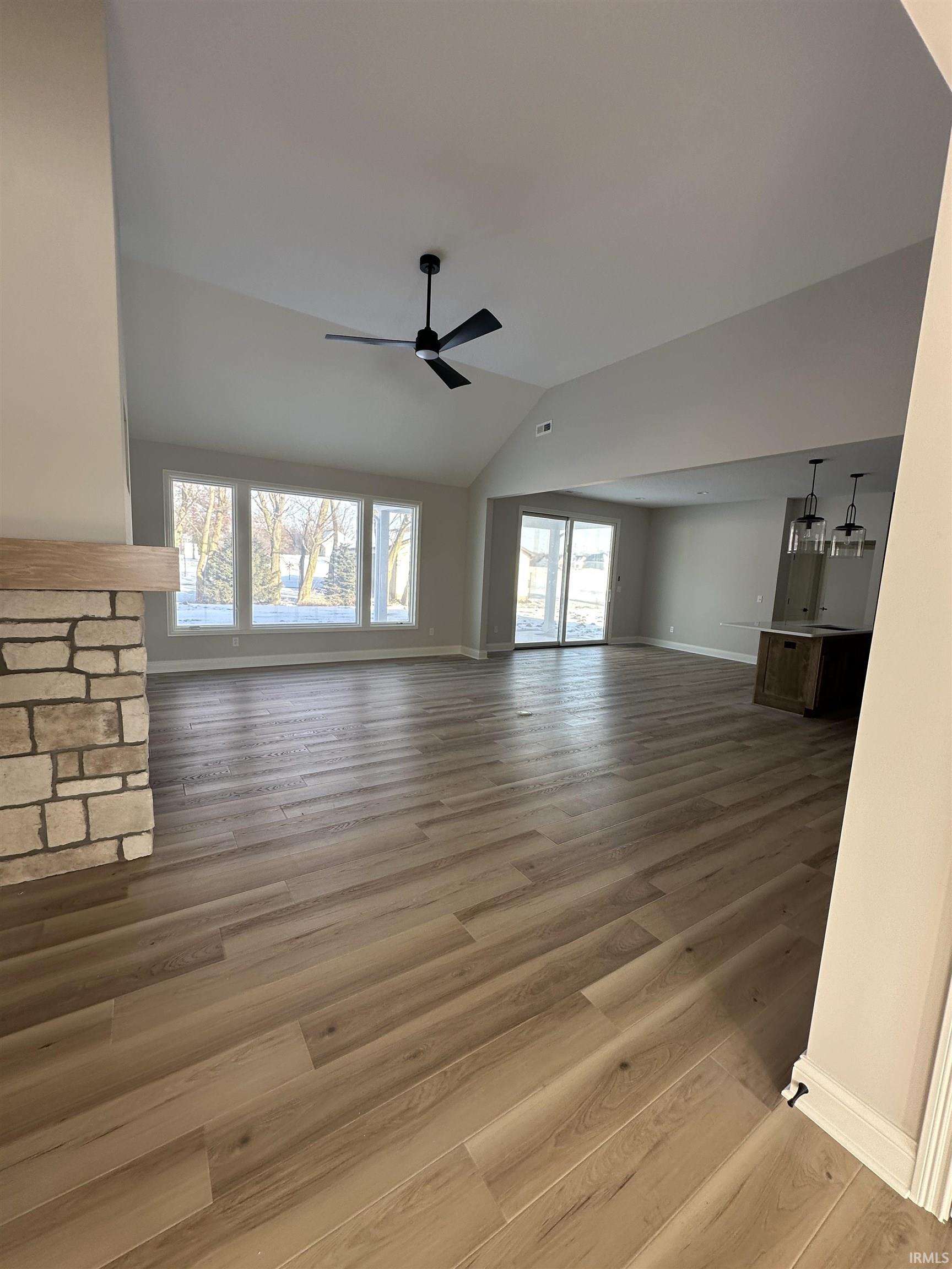 Unfurnished living room with light wood-style floors, vaulted ceiling, and ceiling fan