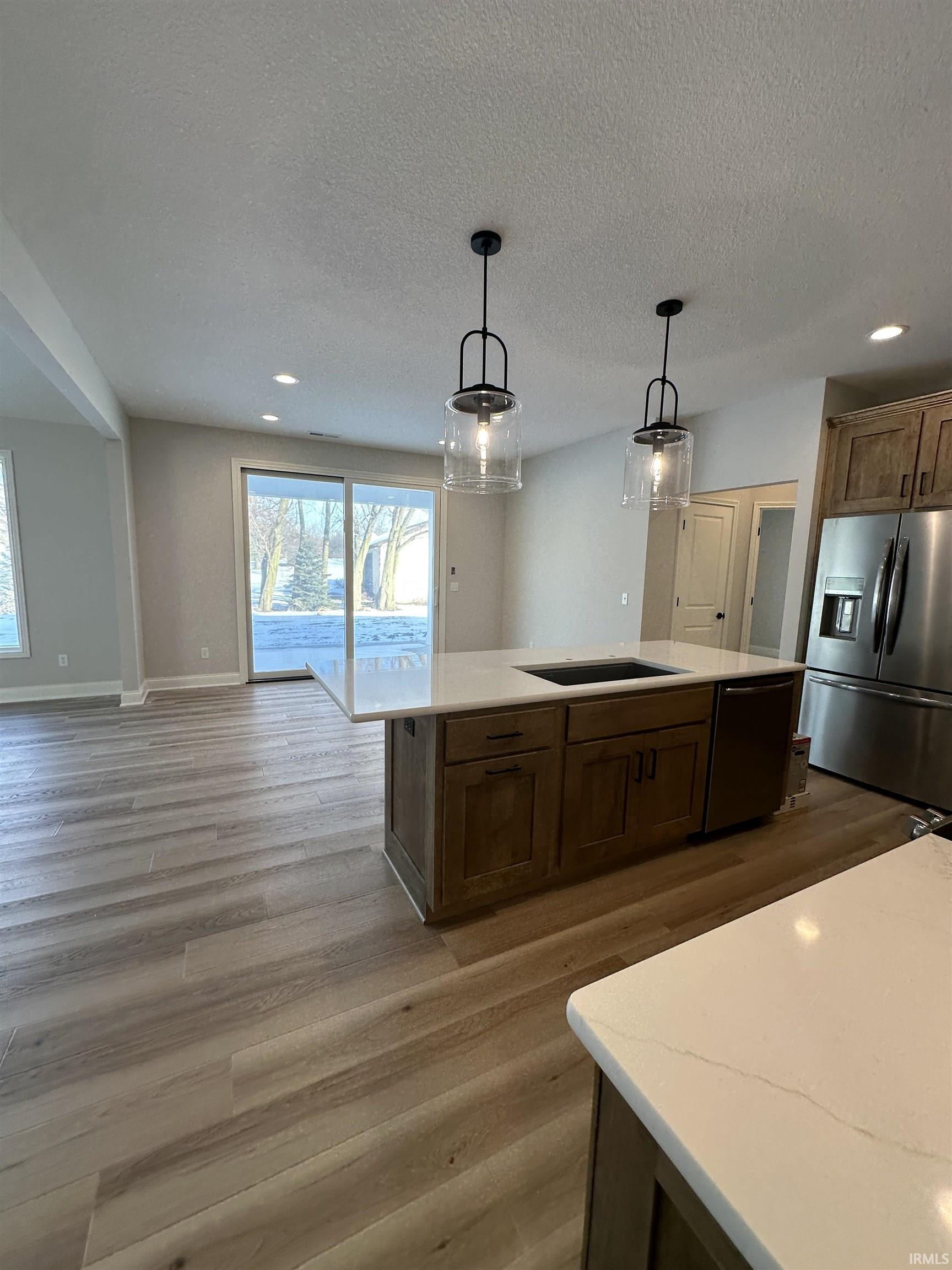 Kitchen featuring hanging light fixtures, stainless steel appliances, recessed lighting, light wood-type flooring, and open floor plan