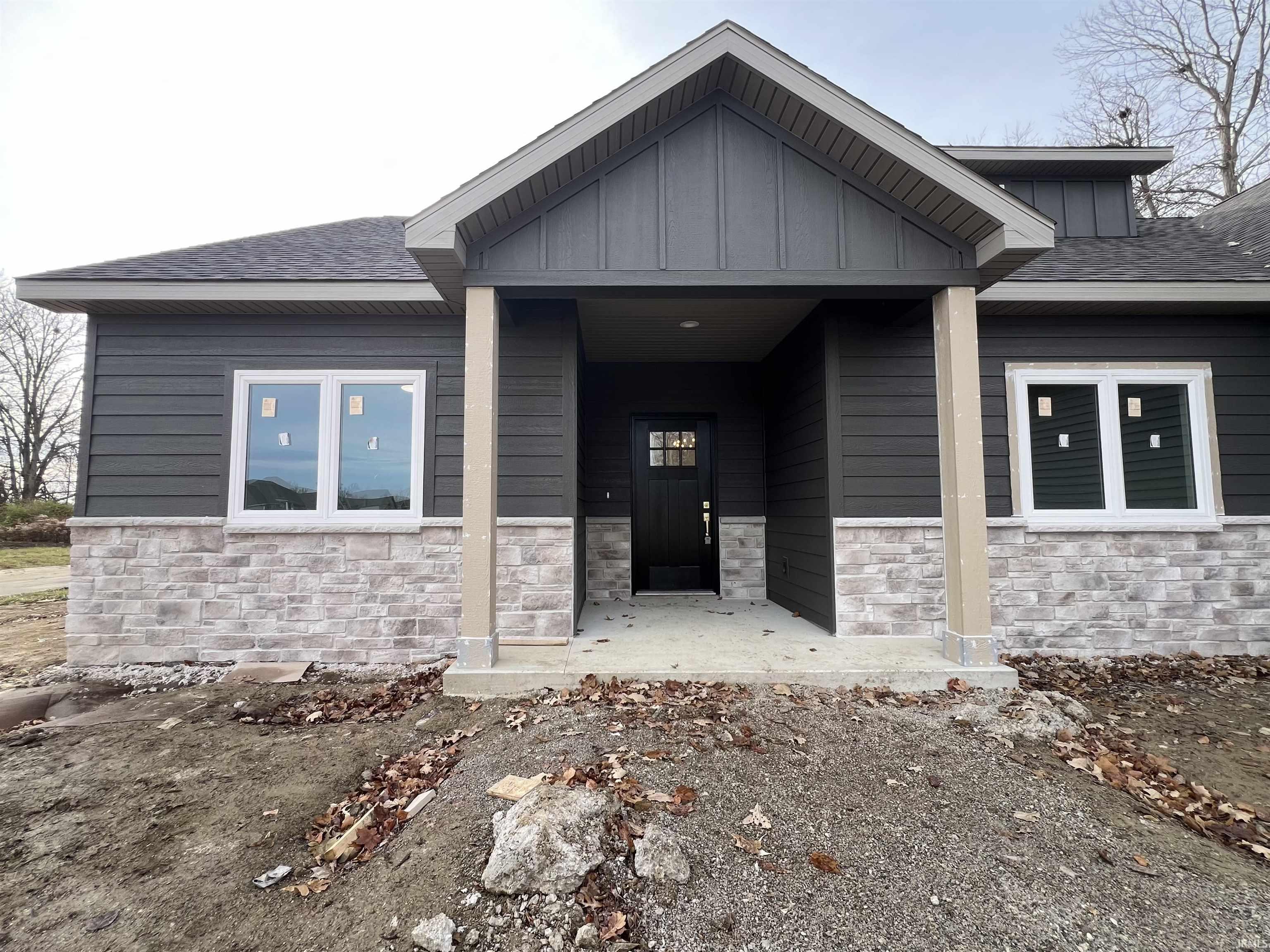 Property entrance with covered porch, stone siding, a shingled roof, and board and batten siding