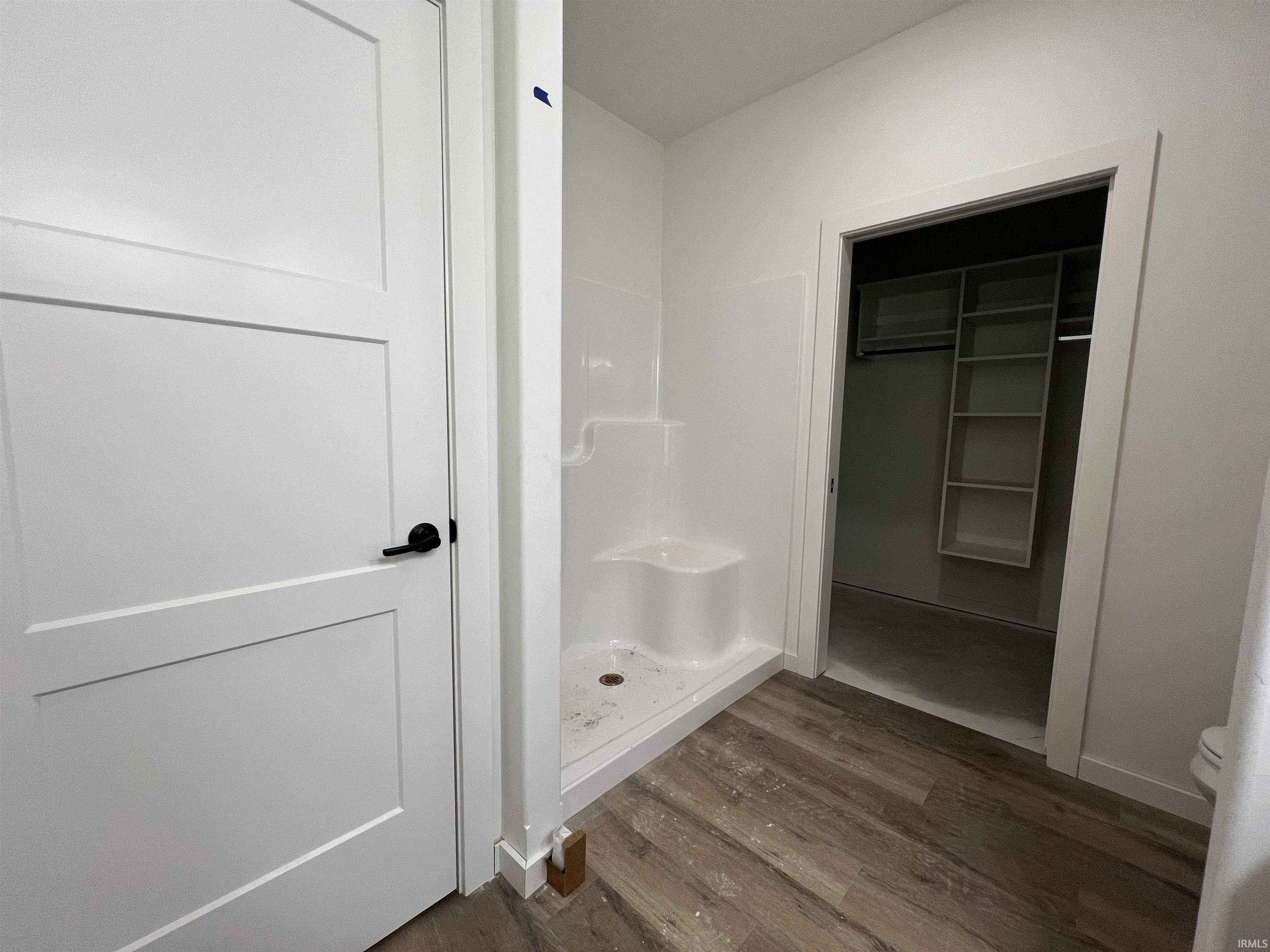 Bathroom featuring a stall shower, wood finished floors, and a walk in closet