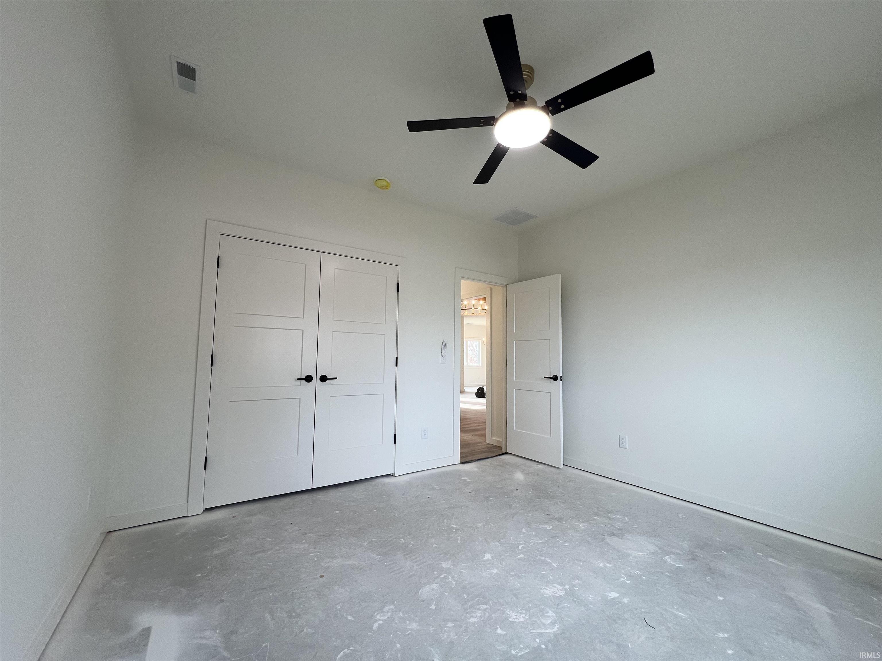 Unfurnished bedroom with ceiling fan, concrete flooring, and a closet