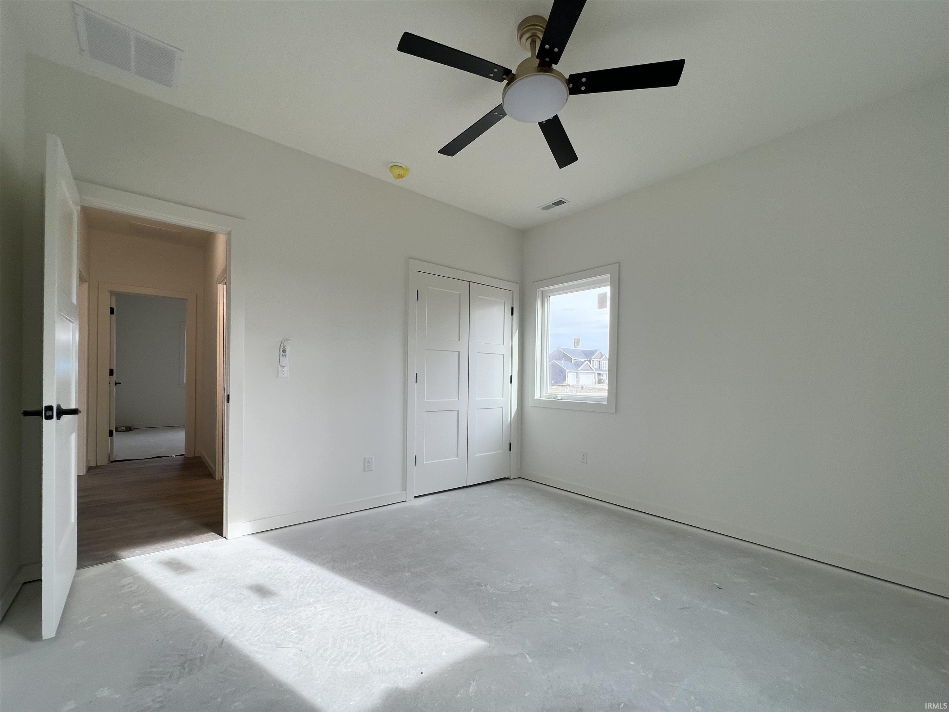 Unfurnished bedroom featuring concrete flooring, ceiling fan, and a closet