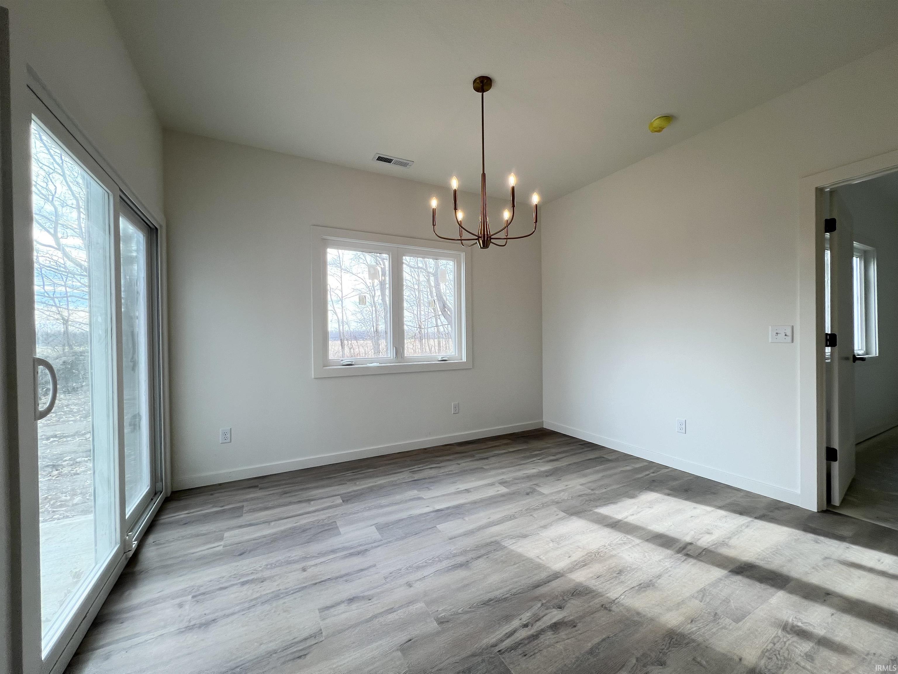 Empty room with a chandelier and light wood-style floors