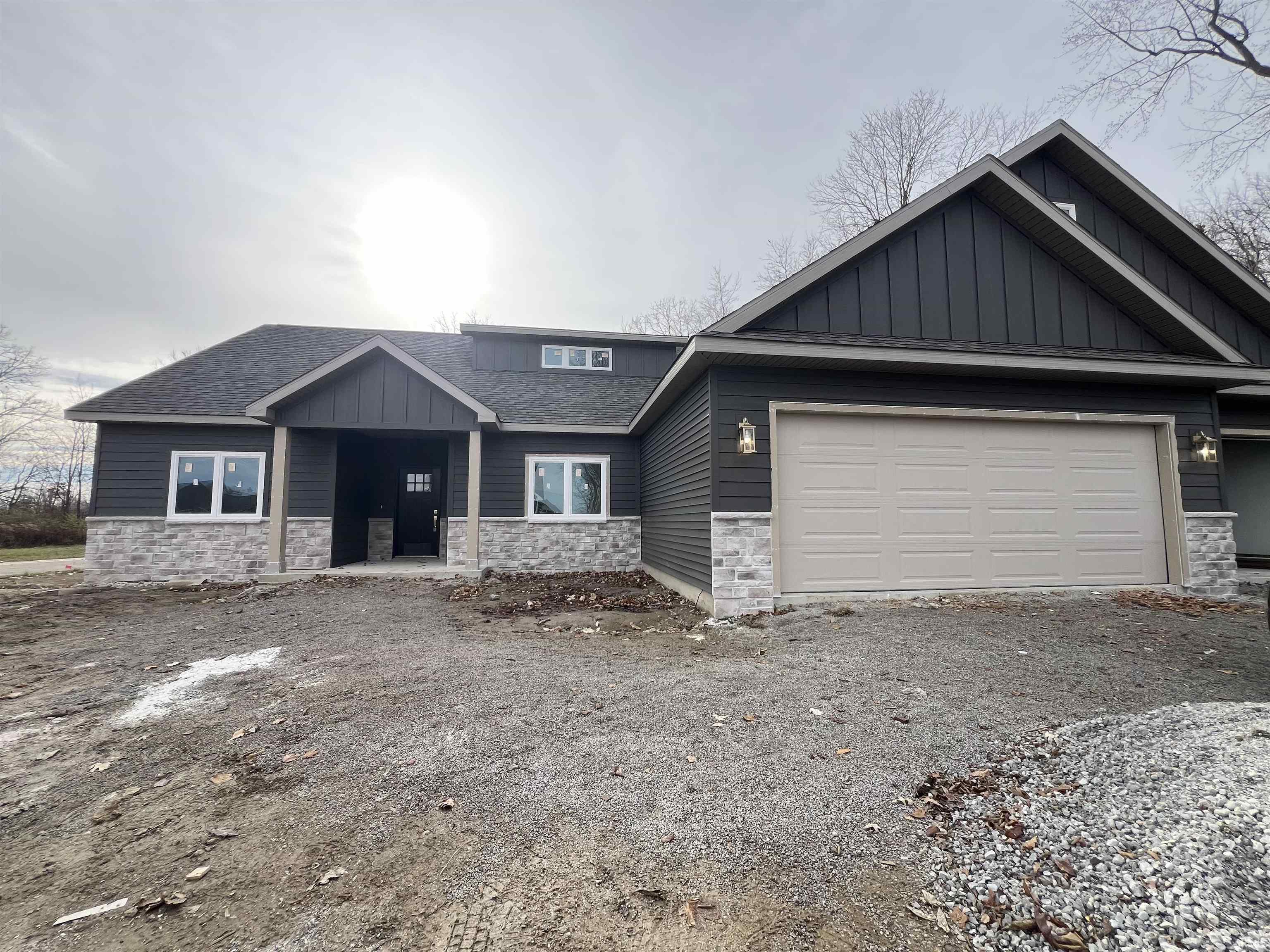 Craftsman-style house featuring stone siding, board and batten siding, a shingled roof, and driveway