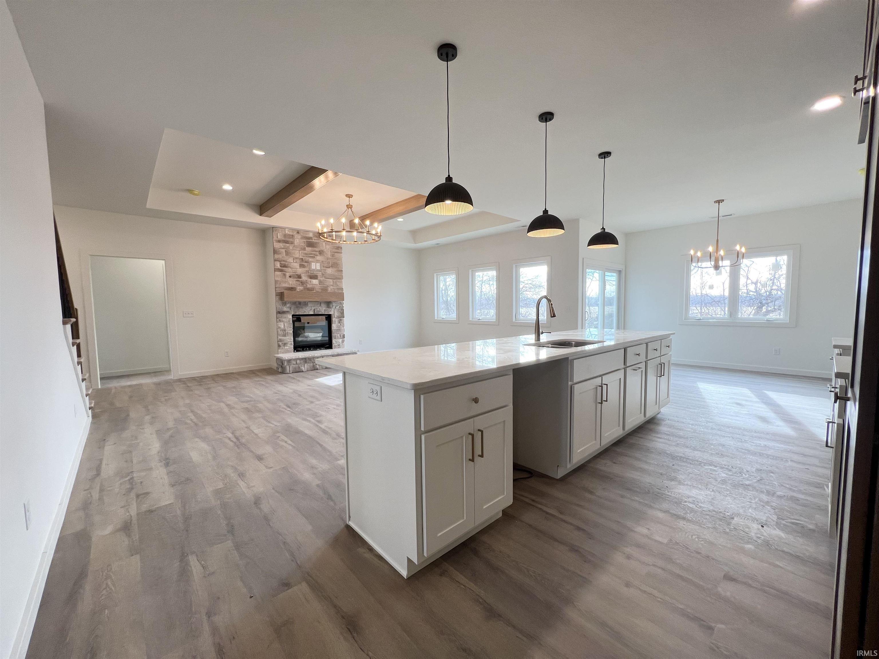 Kitchen featuring a chandelier, open floor plan, light wood-type flooring, a tray ceiling, and recessed lighting