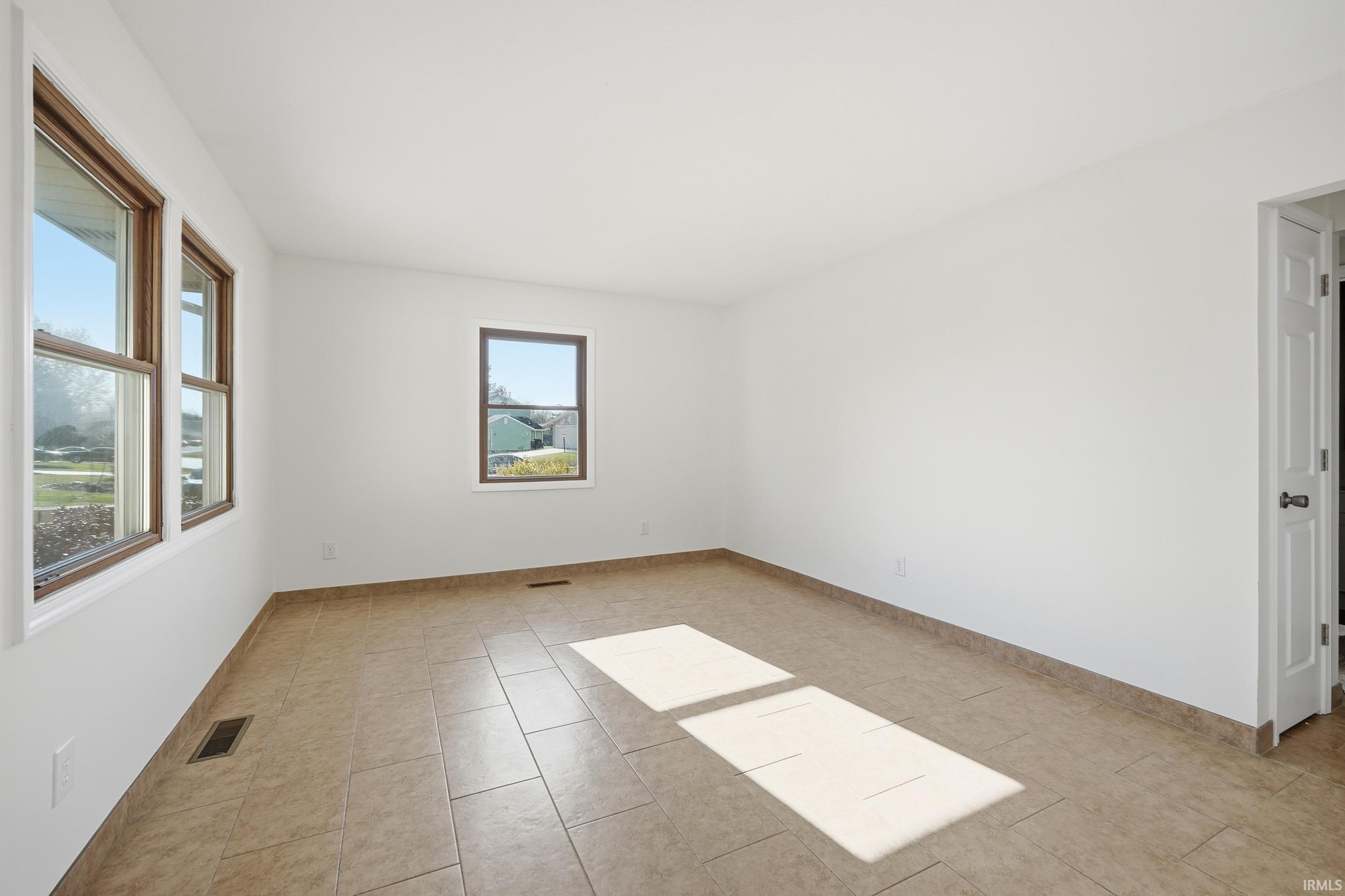 Unfurnished room featuring light tile patterned floors and baseboards
