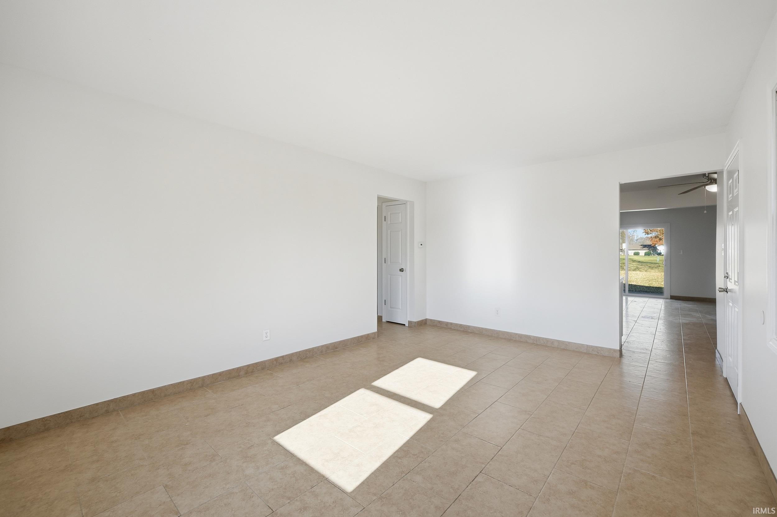 Empty room featuring light tile patterned flooring and ceiling fan