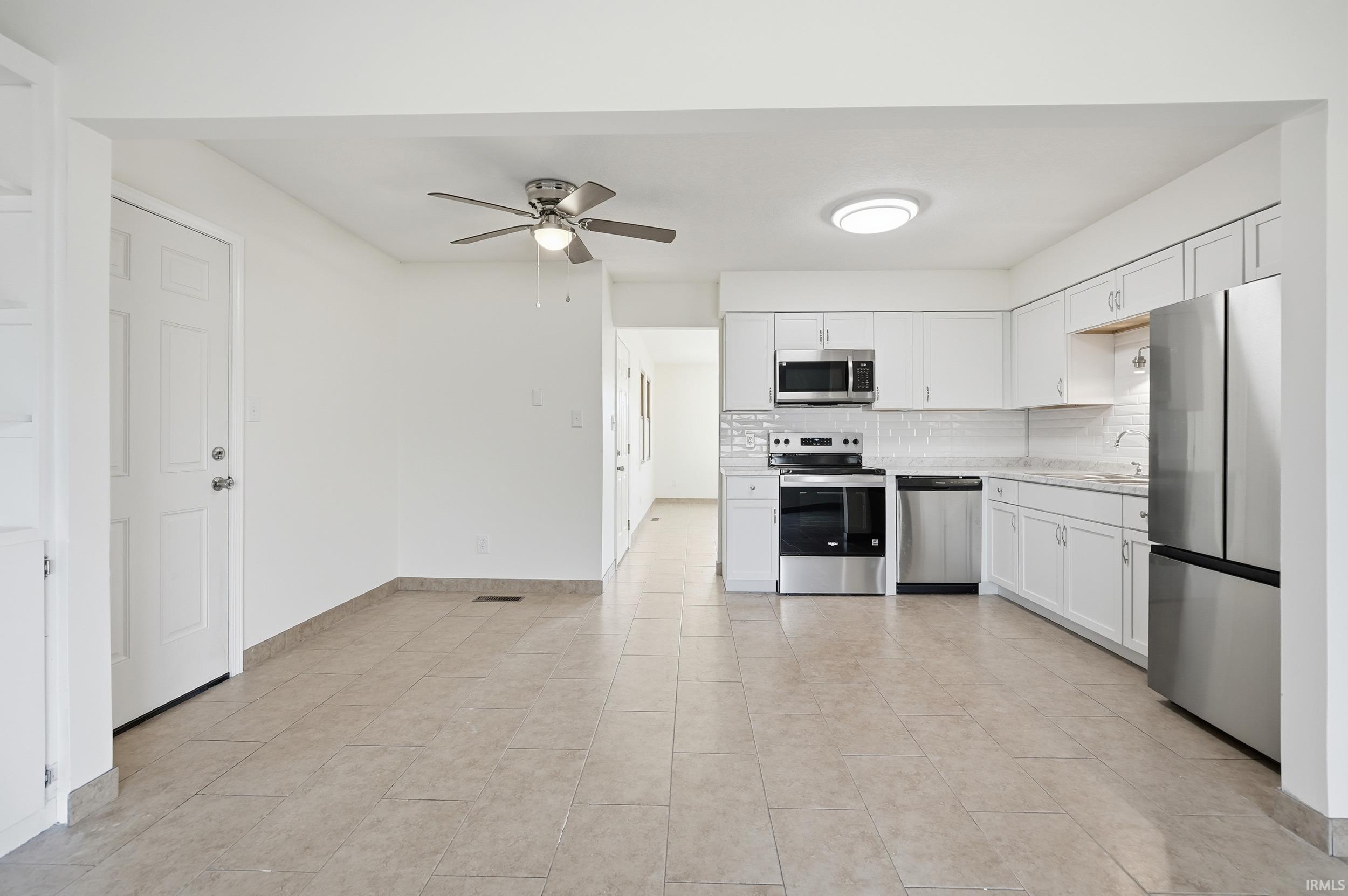 Kitchen with light countertops, appliances with stainless steel finishes, tasteful backsplash, white cabinetry, and ceiling fan