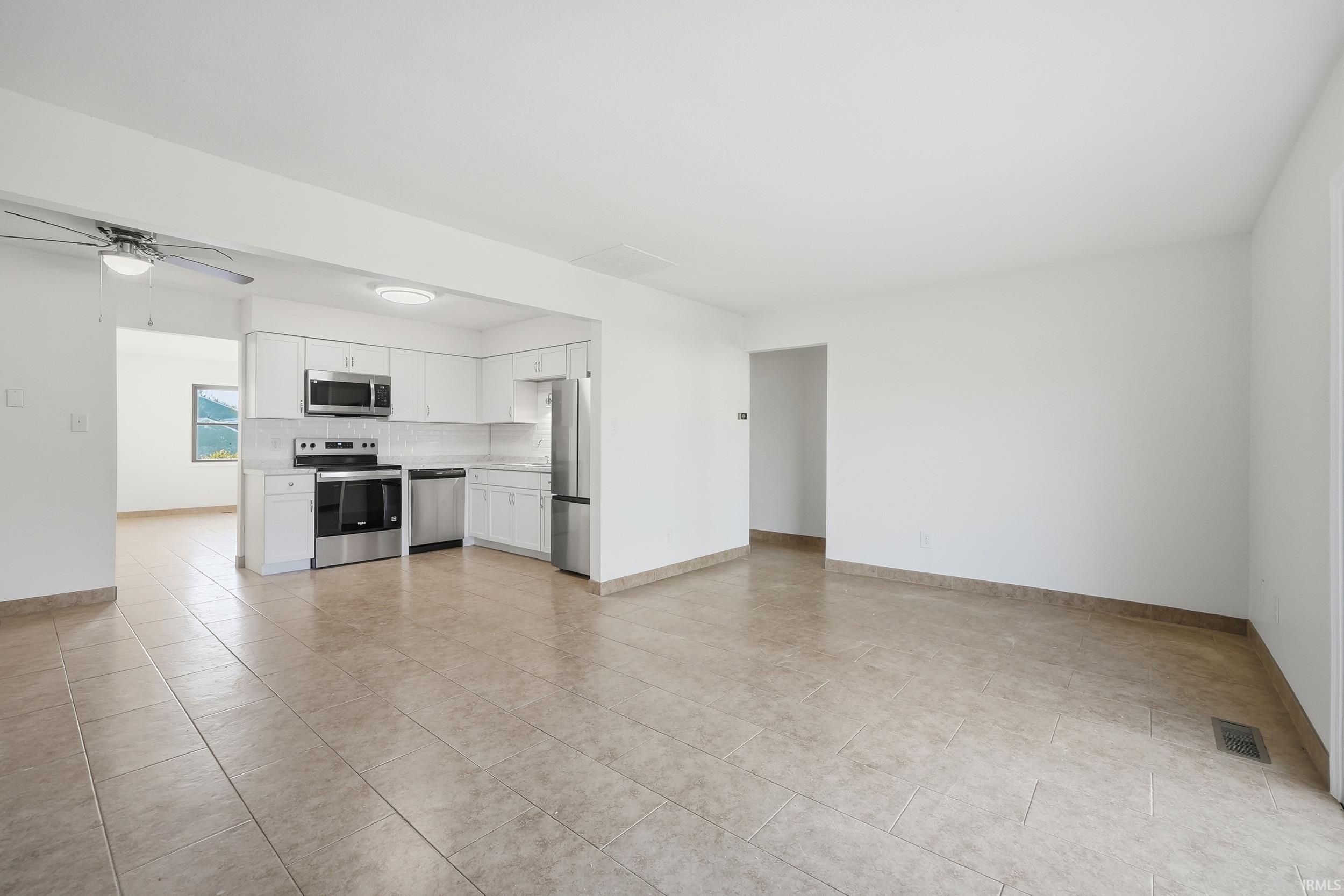 Unfurnished living room with ceiling fan and light tile patterned floors