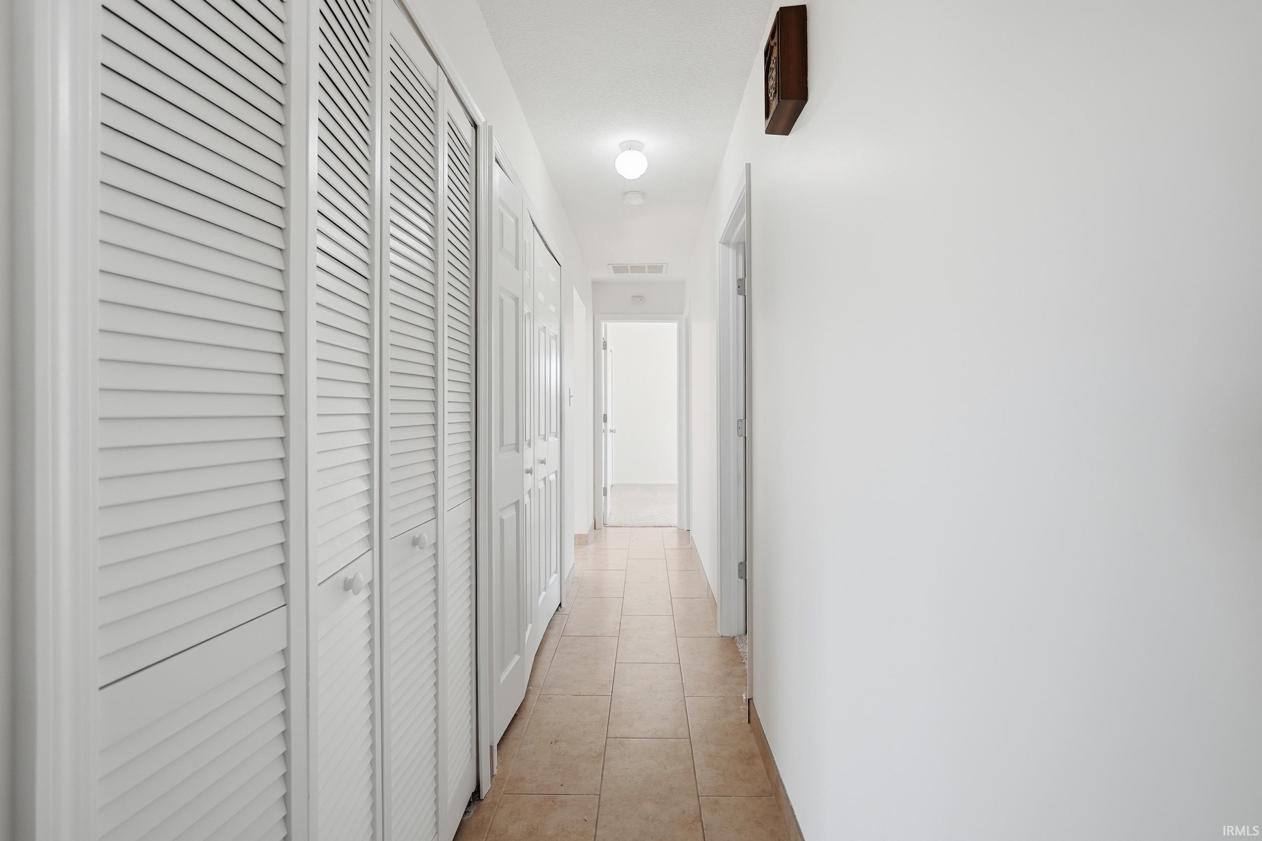 Hallway with light tile patterned floors and baseboards