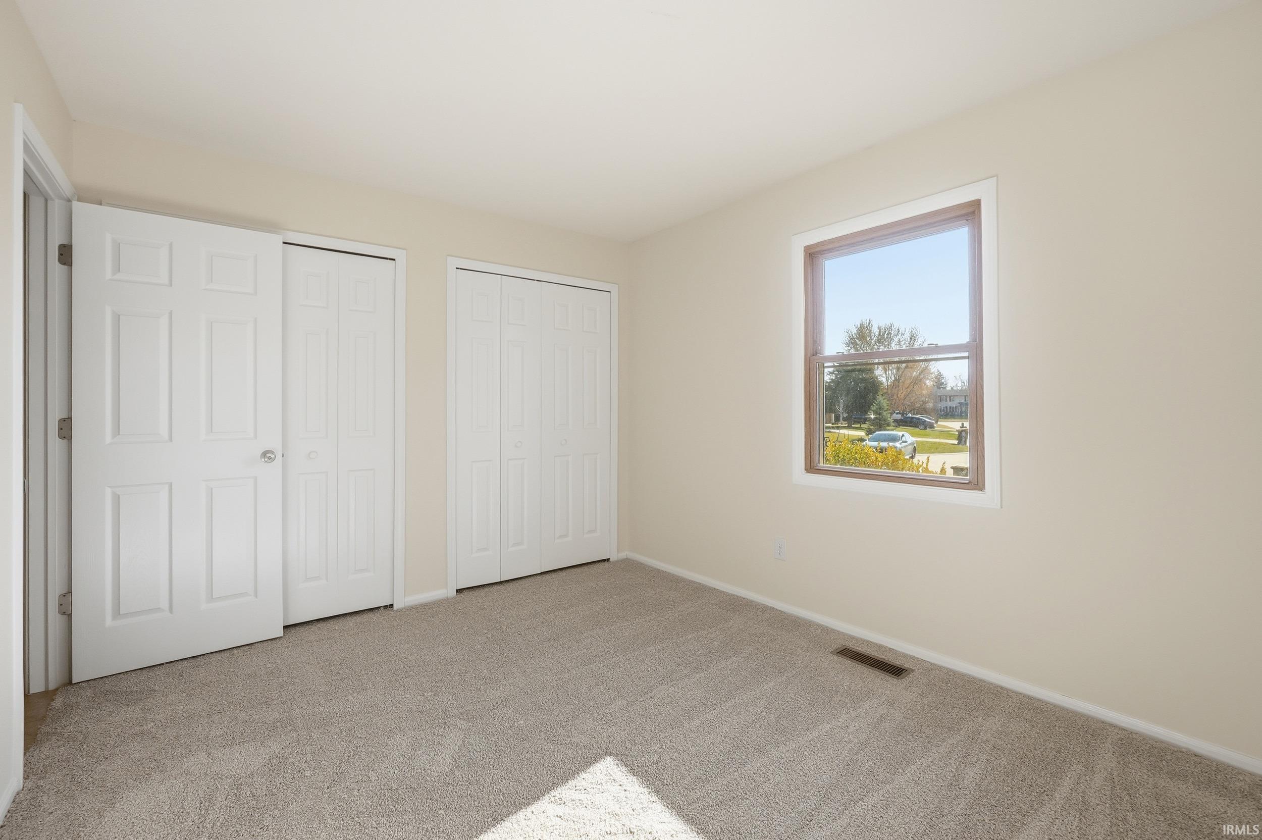 Unfurnished bedroom featuring multiple closets and carpet flooring