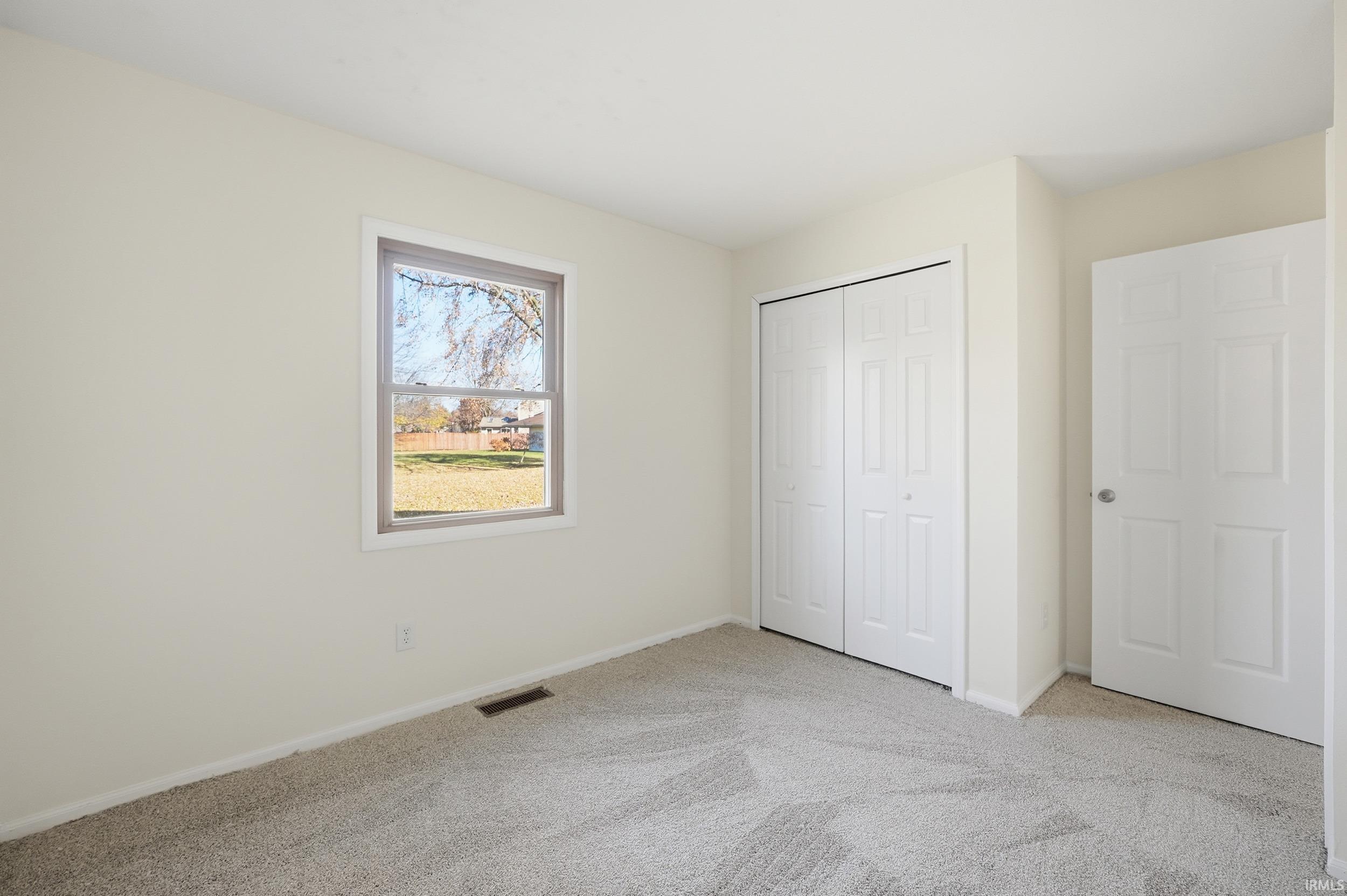 Unfurnished bedroom with light carpet and a closet