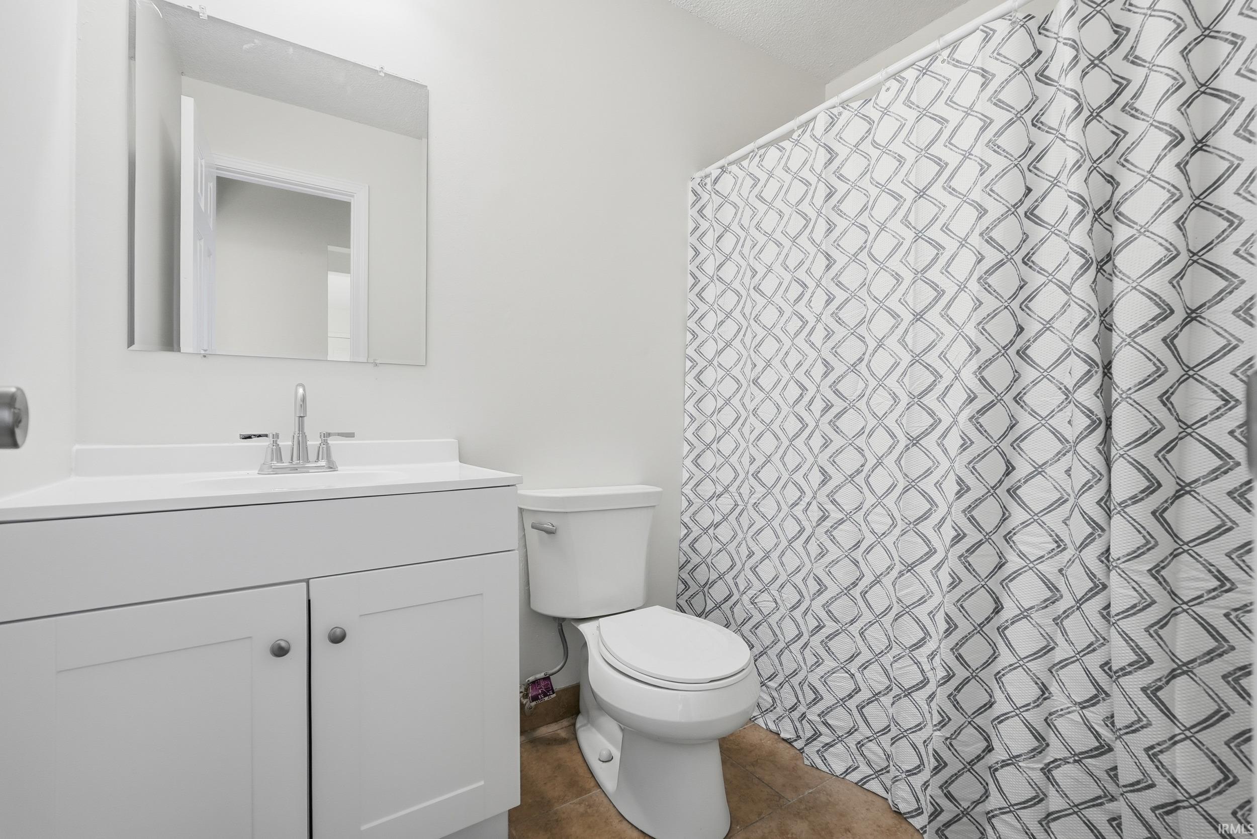 Bathroom featuring a shower with shower curtain, vanity, and tile patterned flooring