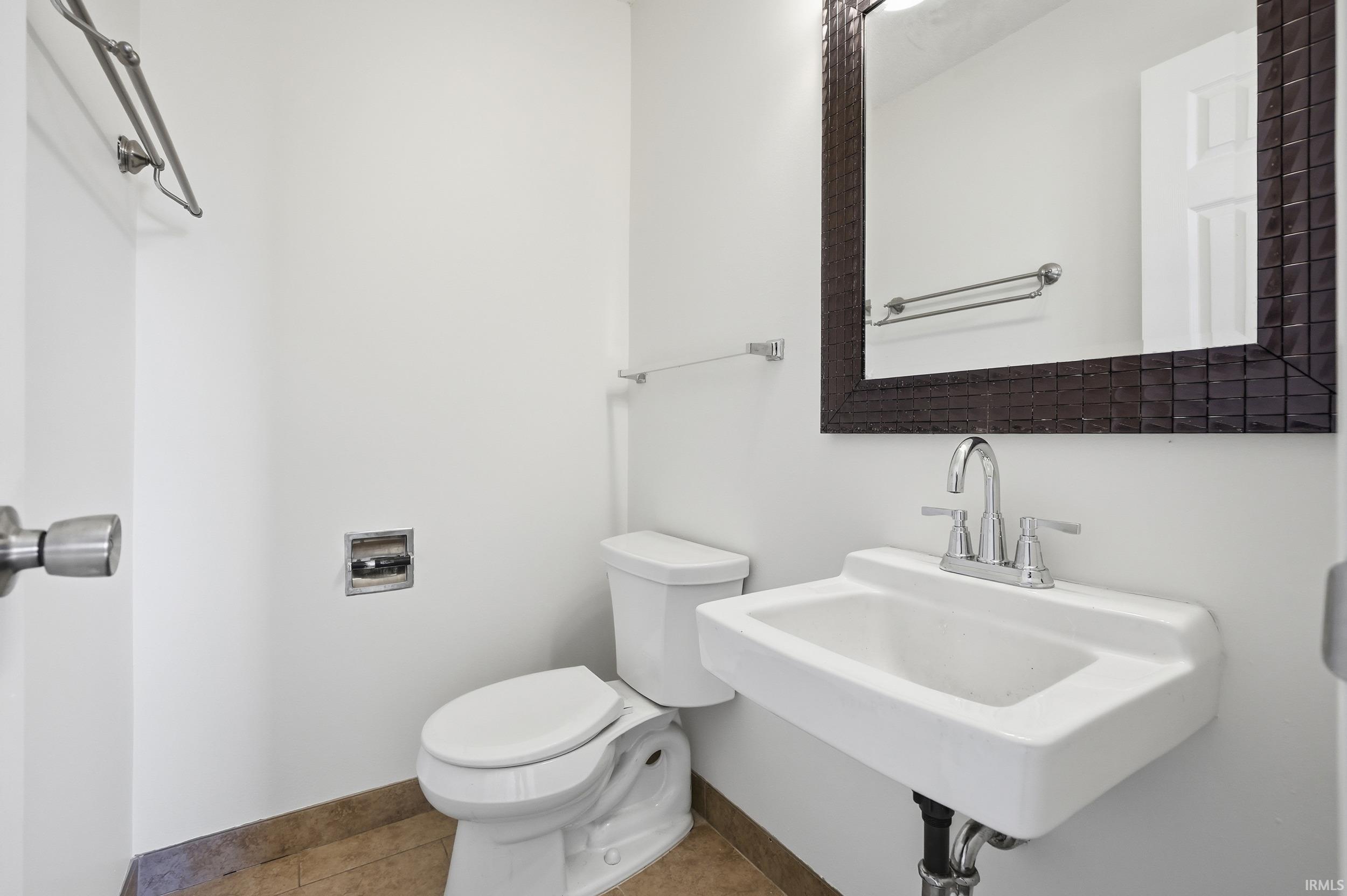 Half bathroom featuring tile patterned flooring and toilet