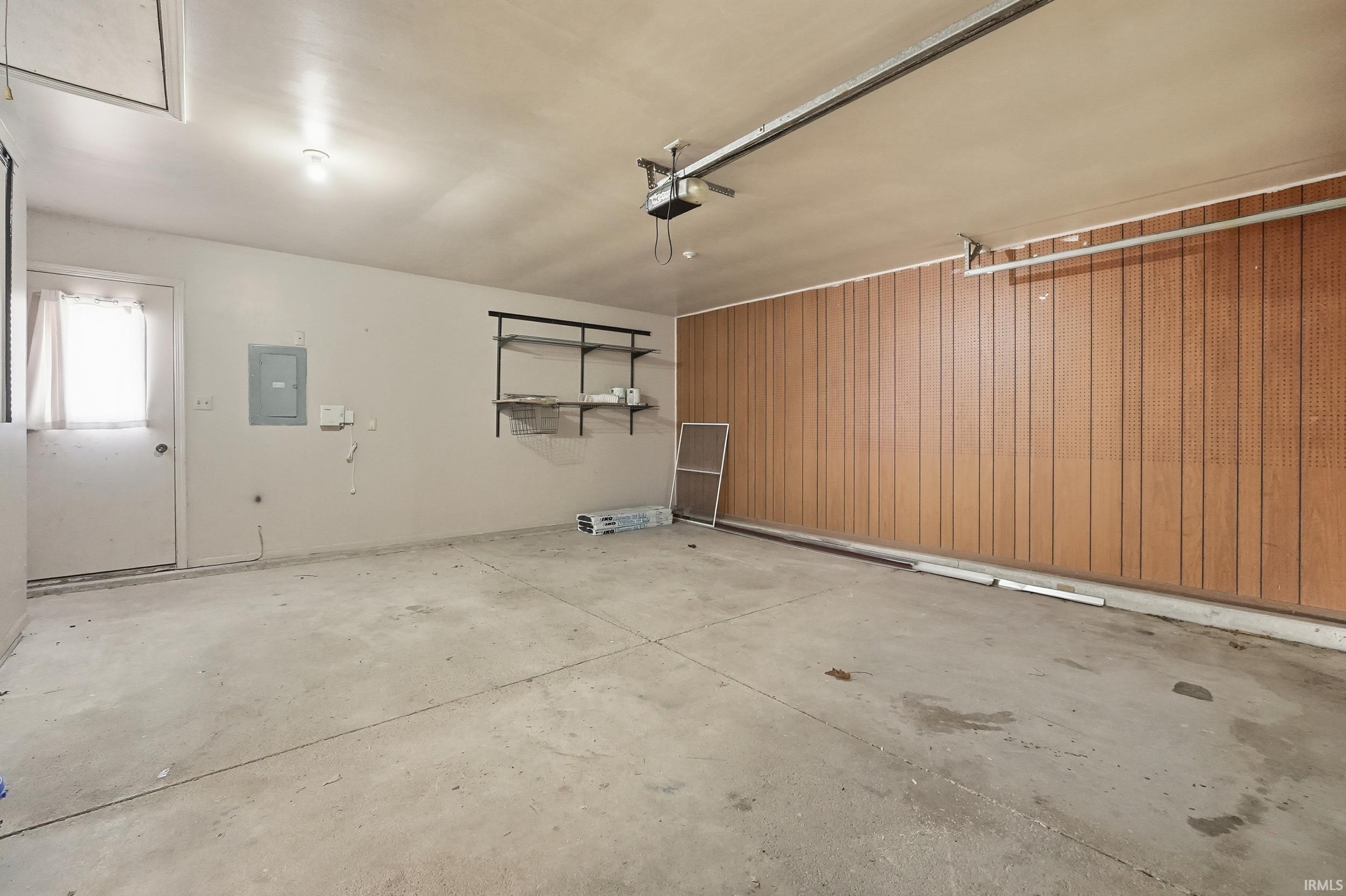 Garage featuring electric panel, wooden walls, and a garage door opener