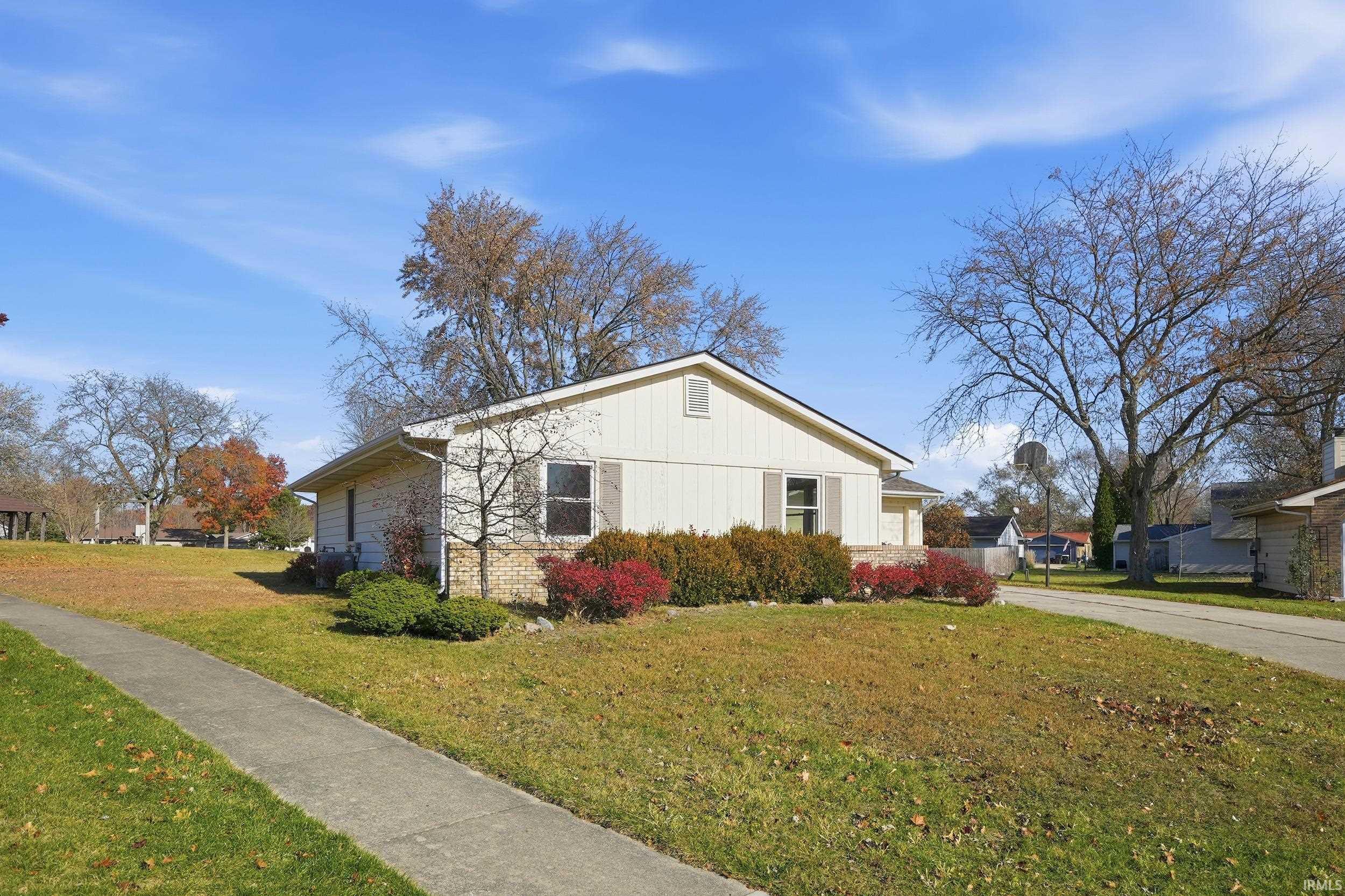 View of property exterior featuring a yard, brick siding, and driveway