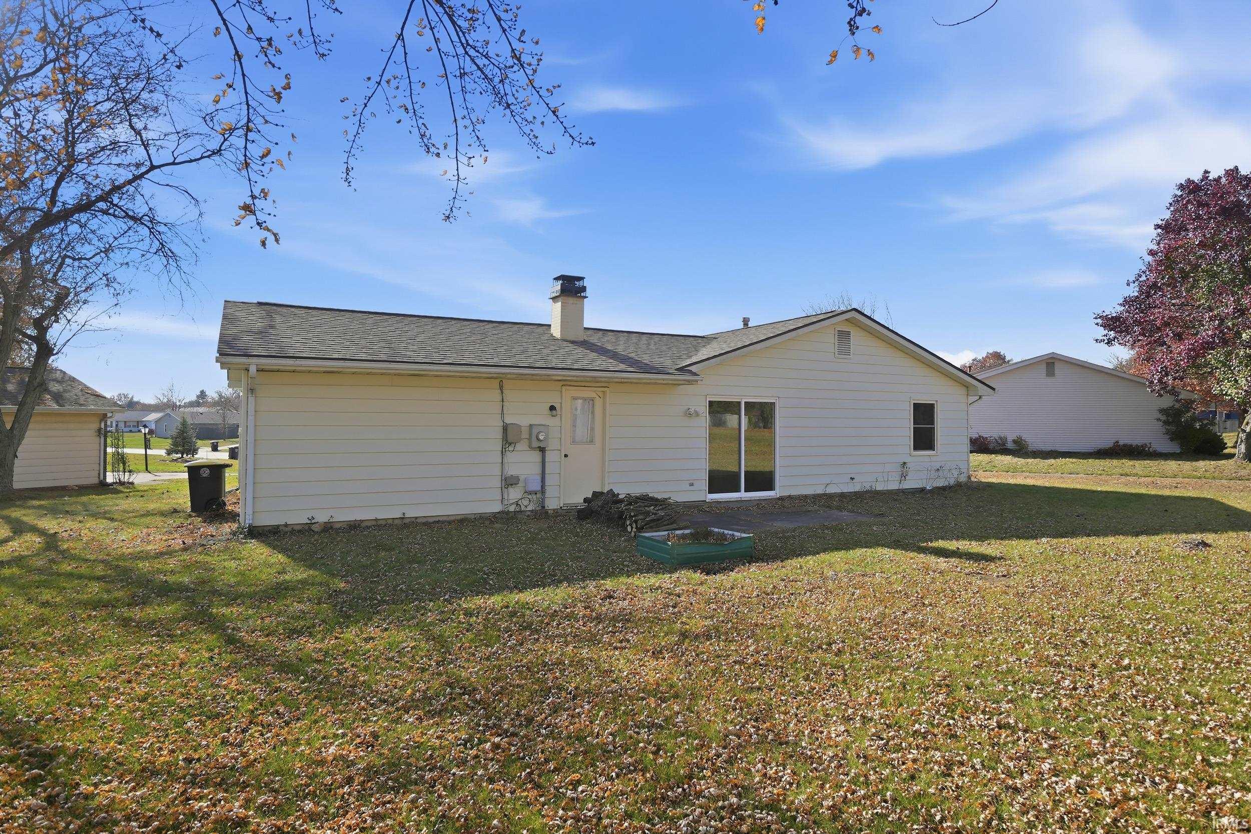 Rear view of property featuring a lawn, a chimney, and roof with shingles