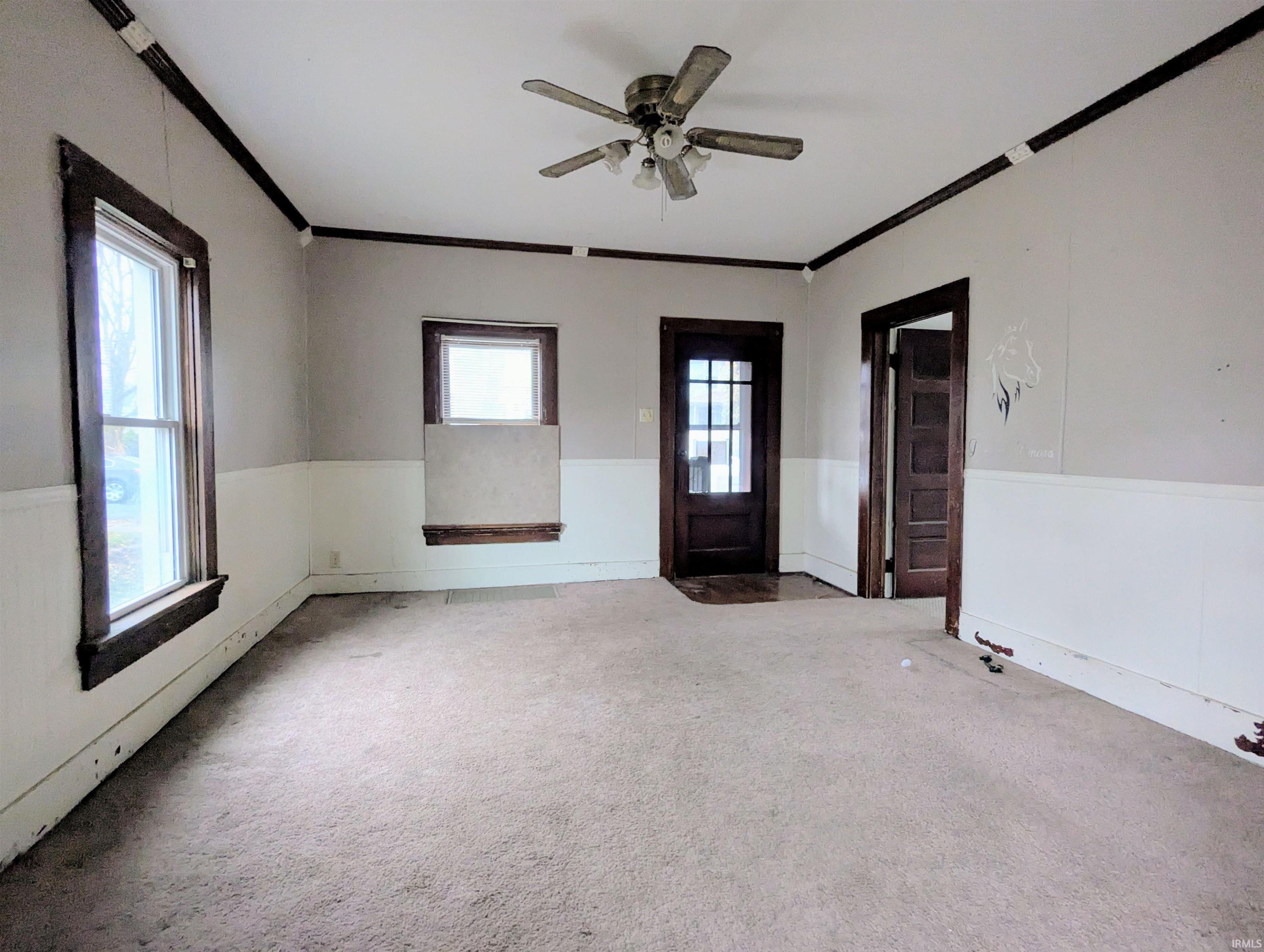 Carpeted spare room featuring crown molding and a ceiling fan