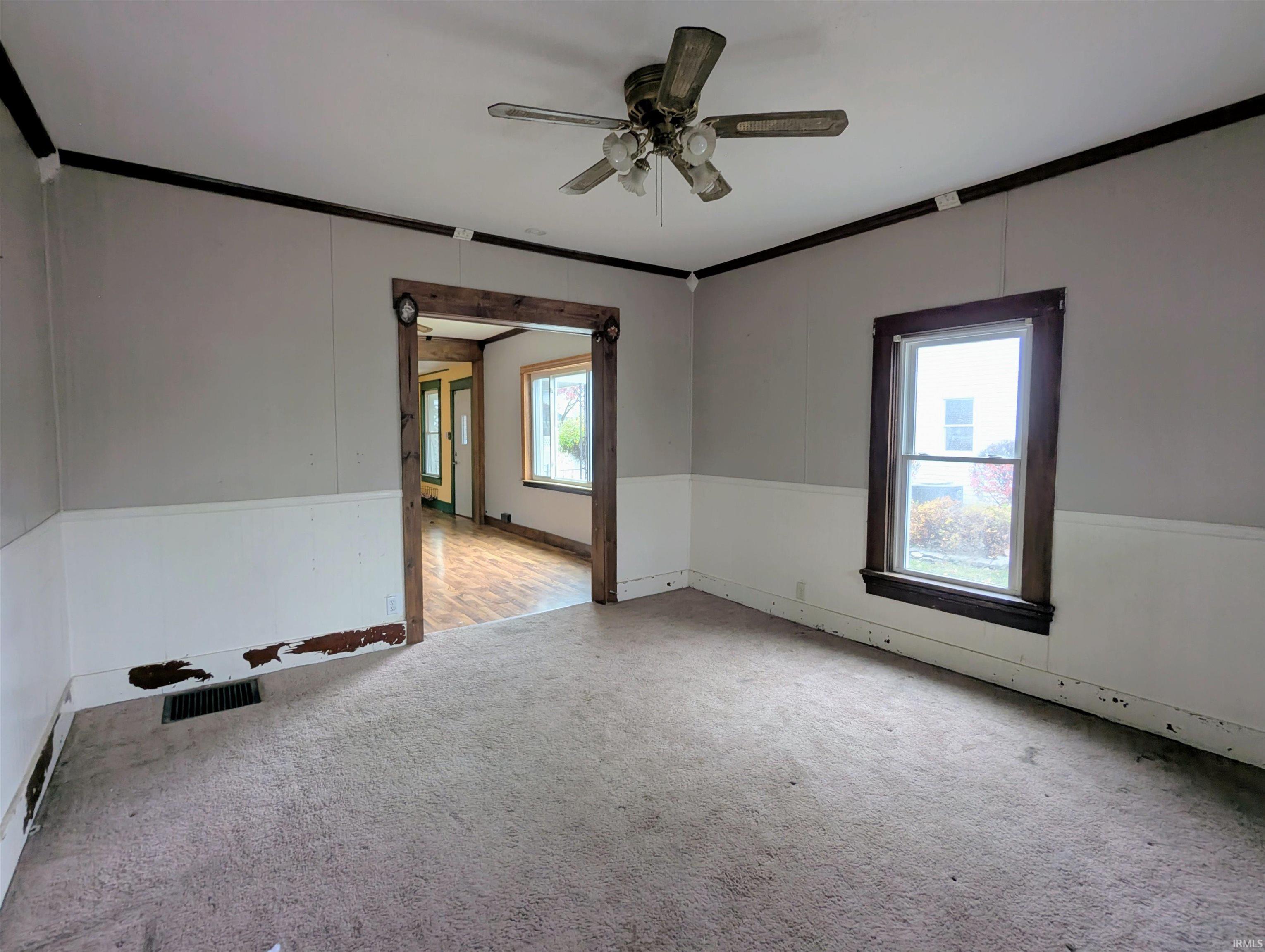 Carpeted spare room featuring ornamental molding and a ceiling fan
