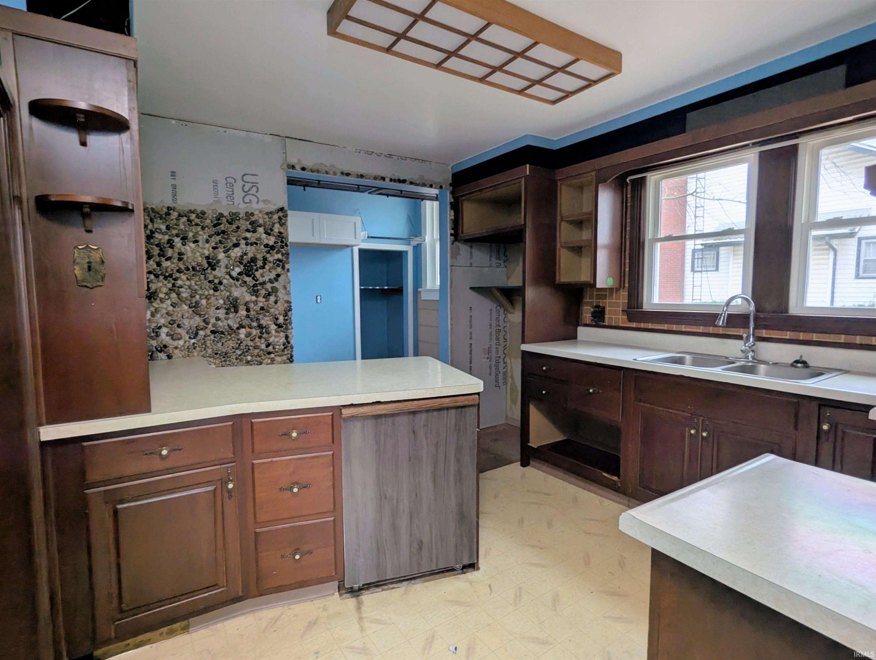 Kitchen with open shelves, light countertops, light flooring, and a peninsula