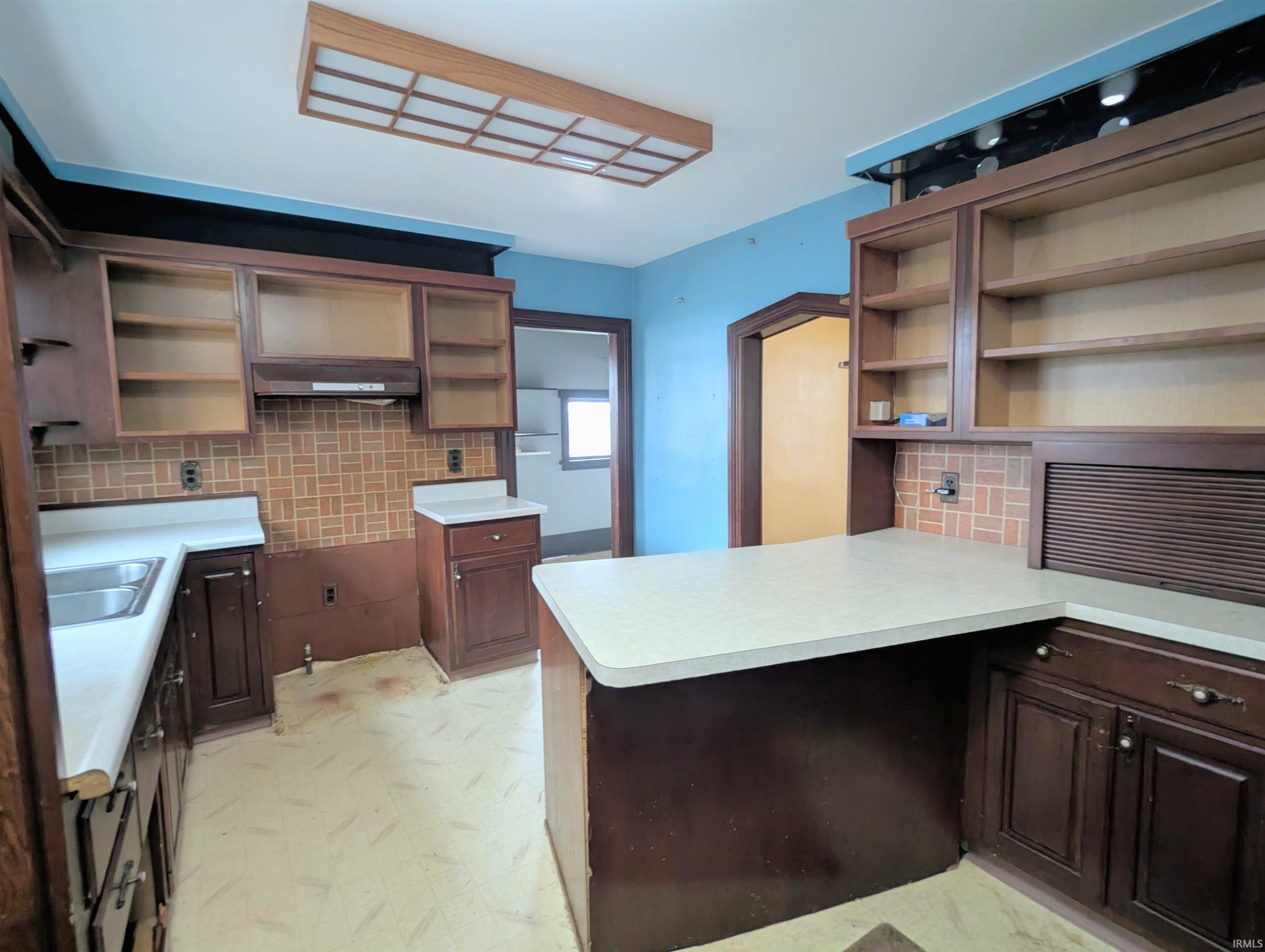 Kitchen featuring open shelves, backsplash, light floors, and light countertops
