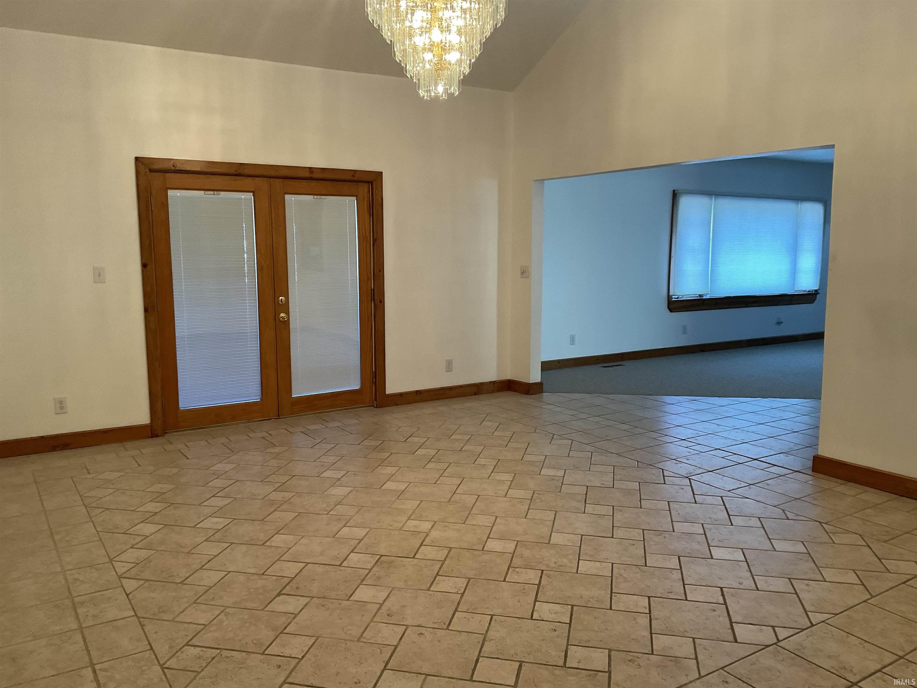 Dining room with a chandelier, high vaulted ceiling, and french doors leading to 3 season room