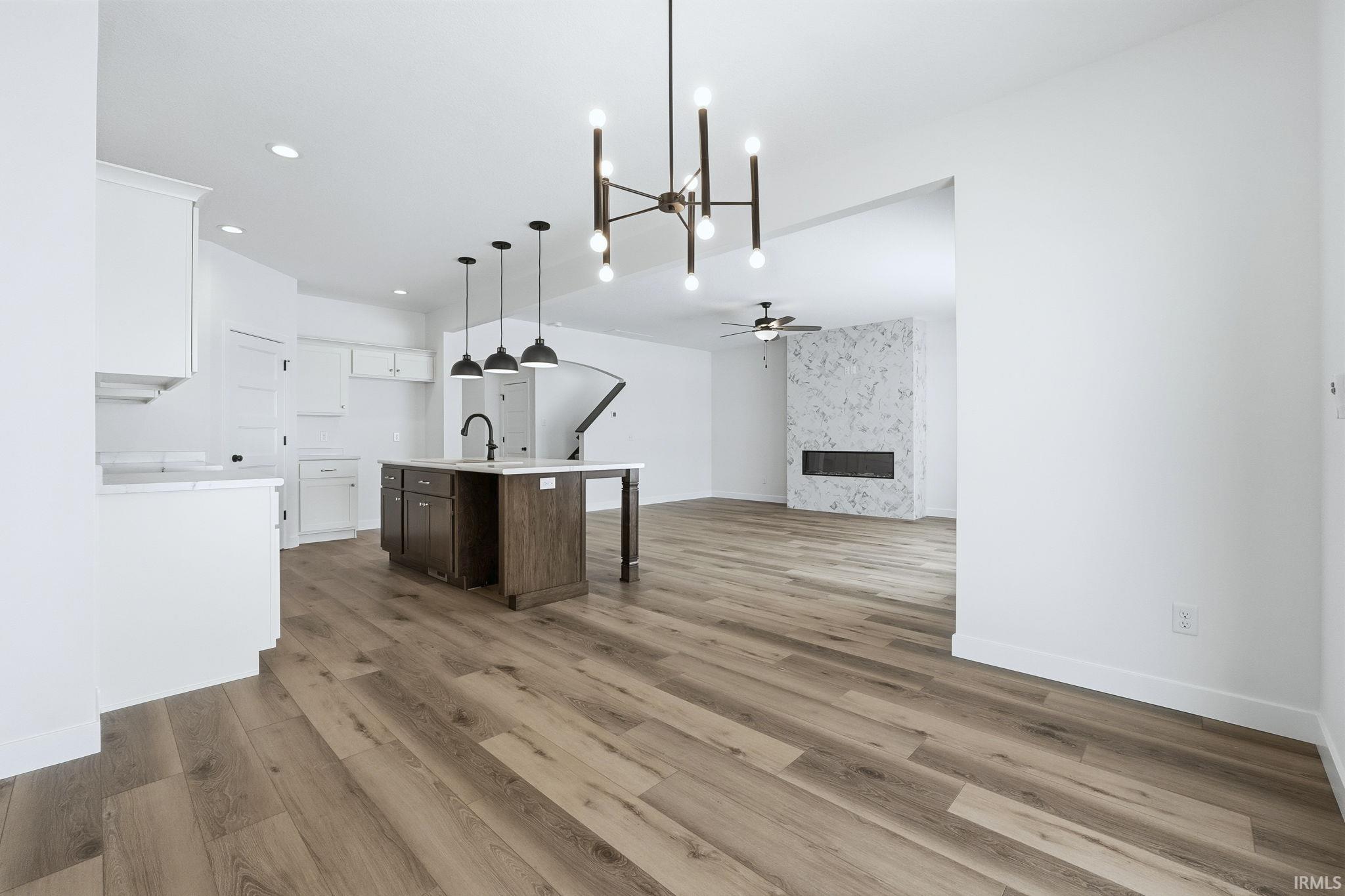 Kitchen featuring a chandelier, a kitchen island with sink, a fireplace, a breakfast bar, and dark brown cabinetry