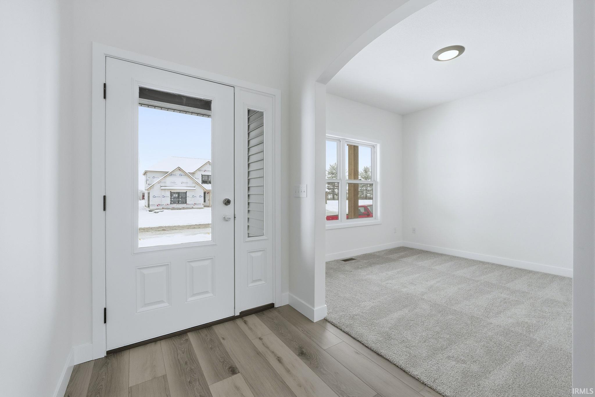 Foyer entrance featuring arched walkways and light wood-style floors