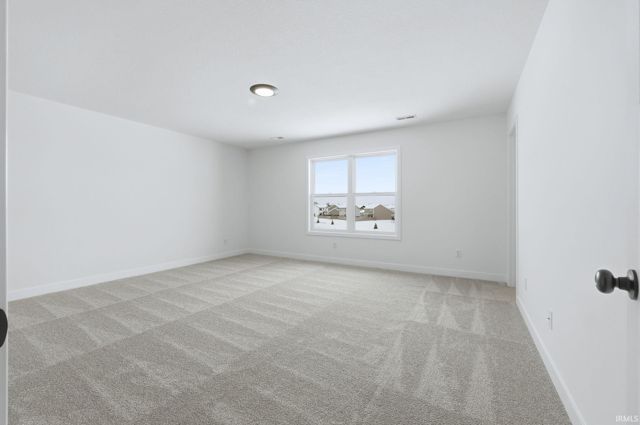 Spare room featuring light colored carpet and baseboards