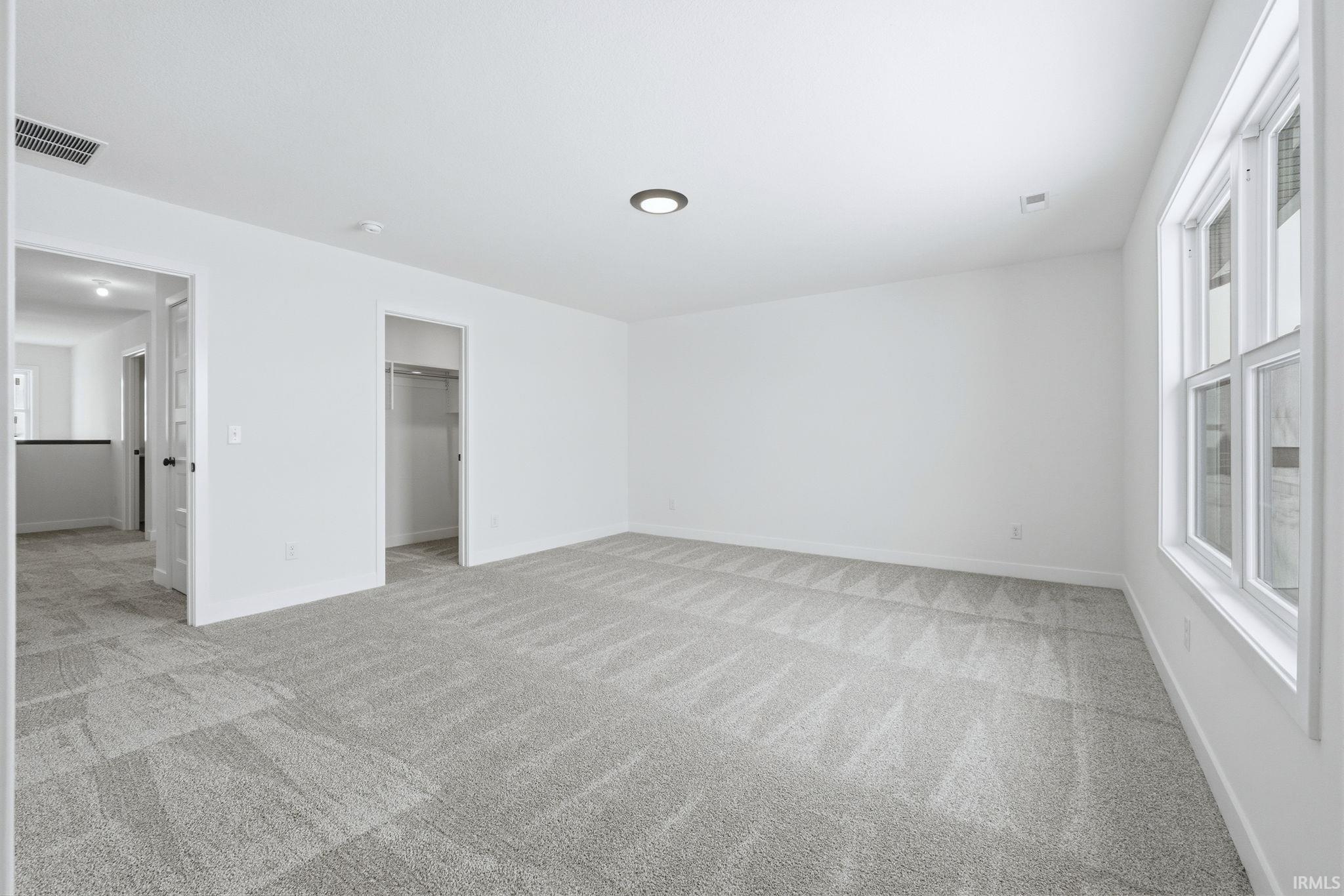 Unfurnished bedroom with a spacious closet and light carpet