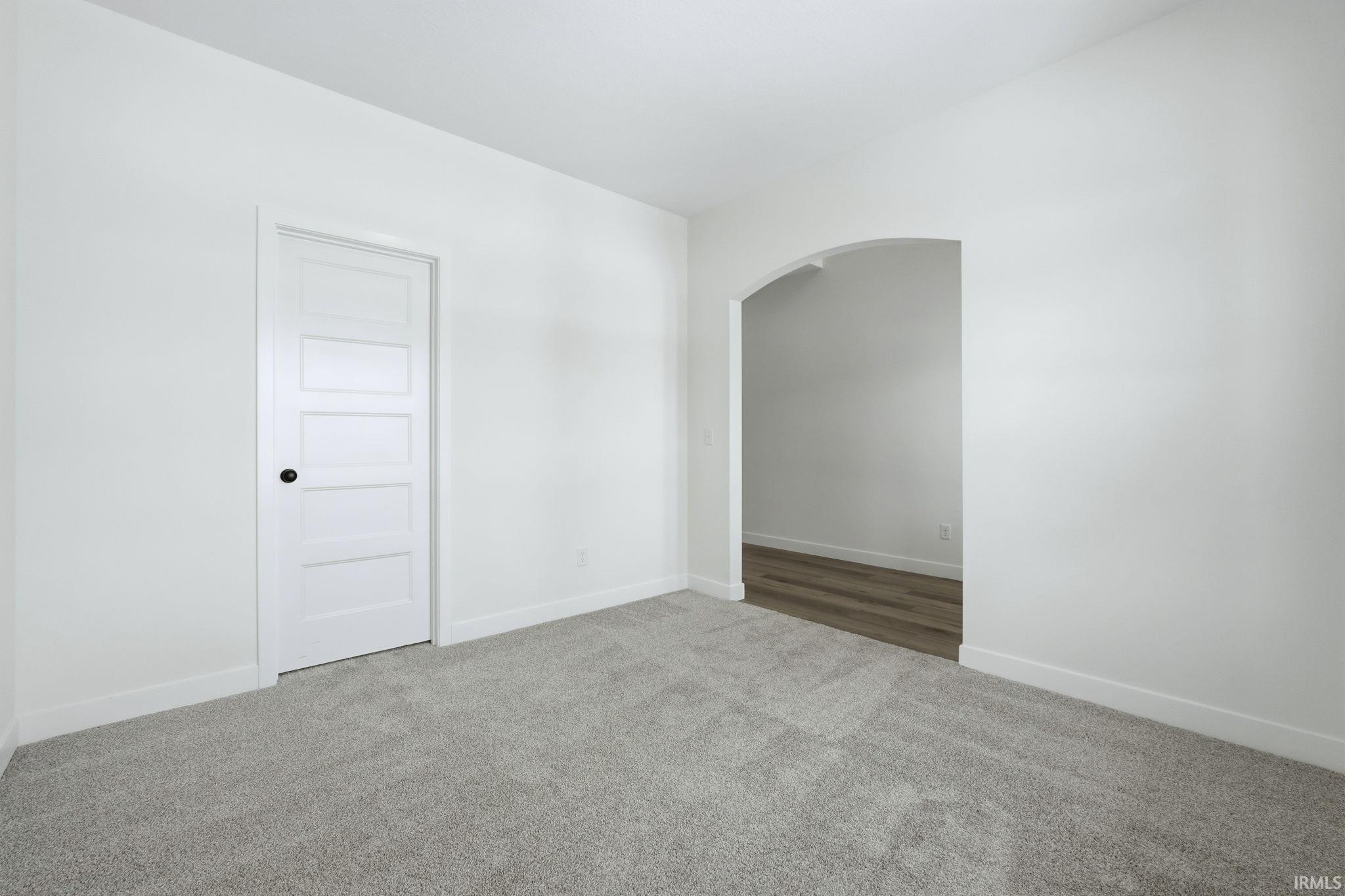Carpeted spare room with arched walkways and baseboards