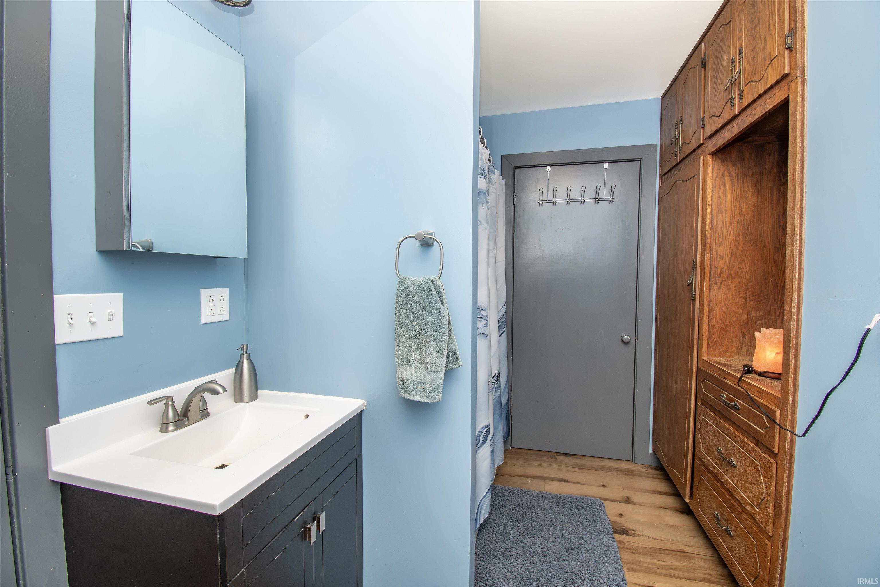 Full bathroom featuring vanity, curtained shower, and light wood-style floors