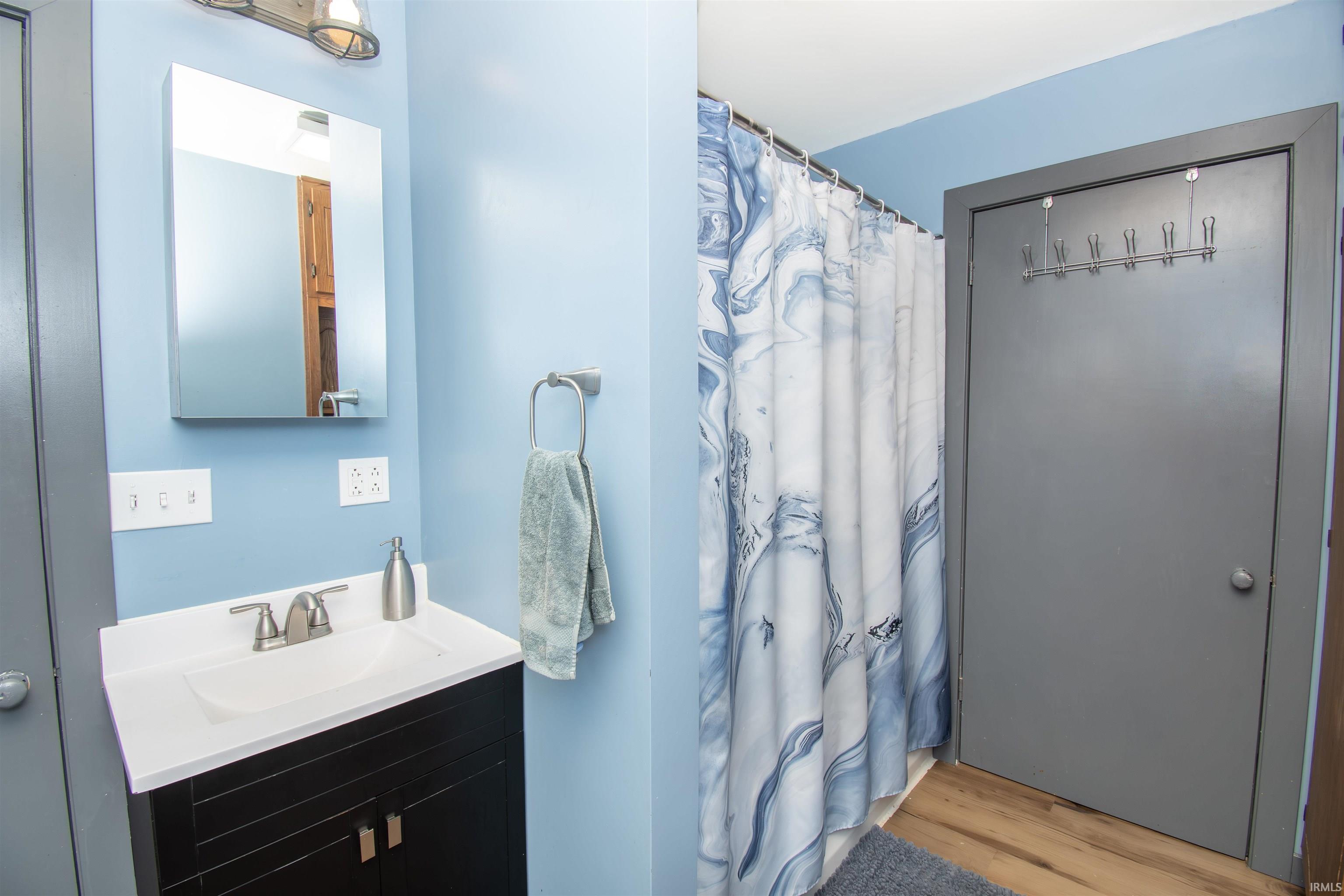 Bathroom featuring curtained shower, vanity, and light wood-style floors