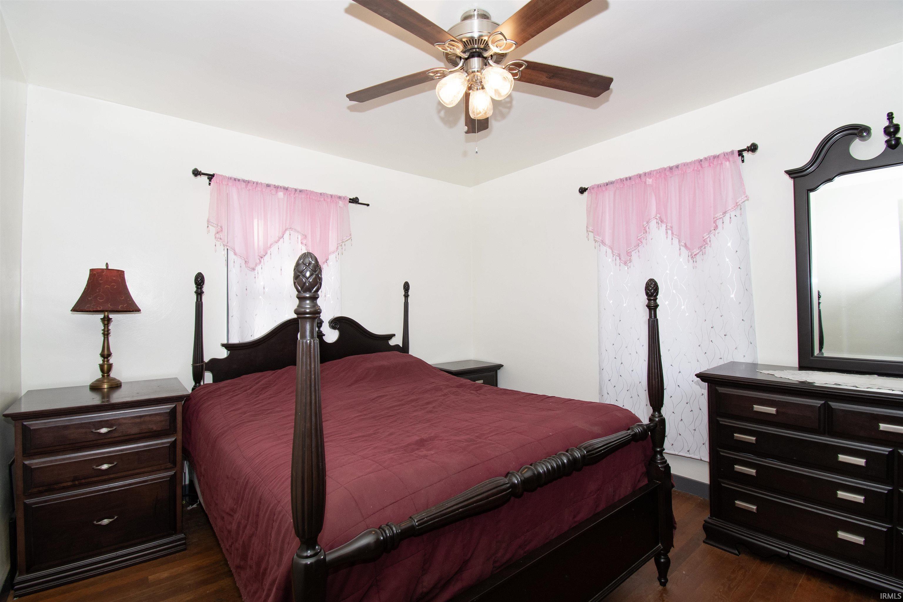 Bedroom with a ceiling fan and dark wood-type flooring