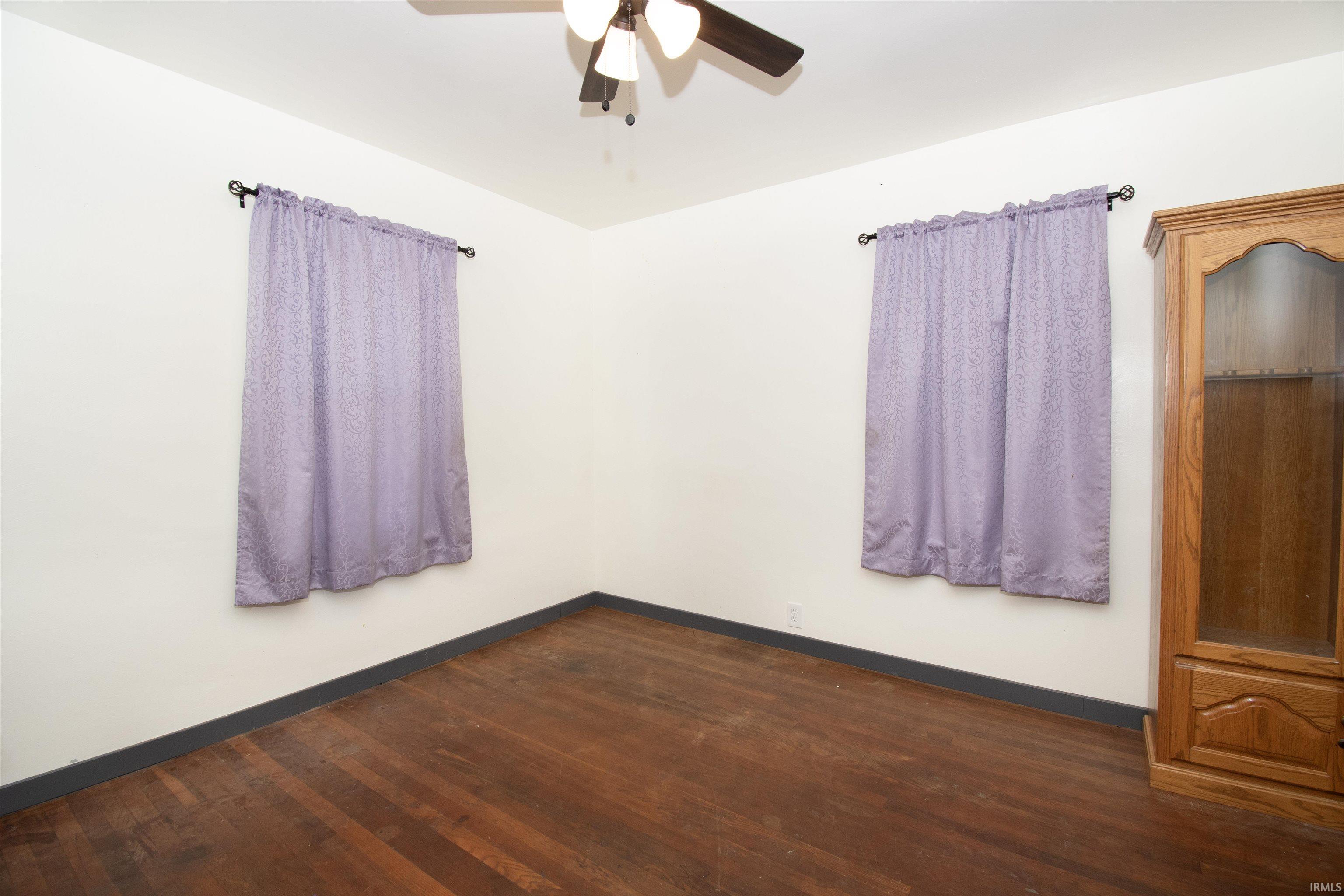 Spare room with dark wood-style floors and a ceiling fan