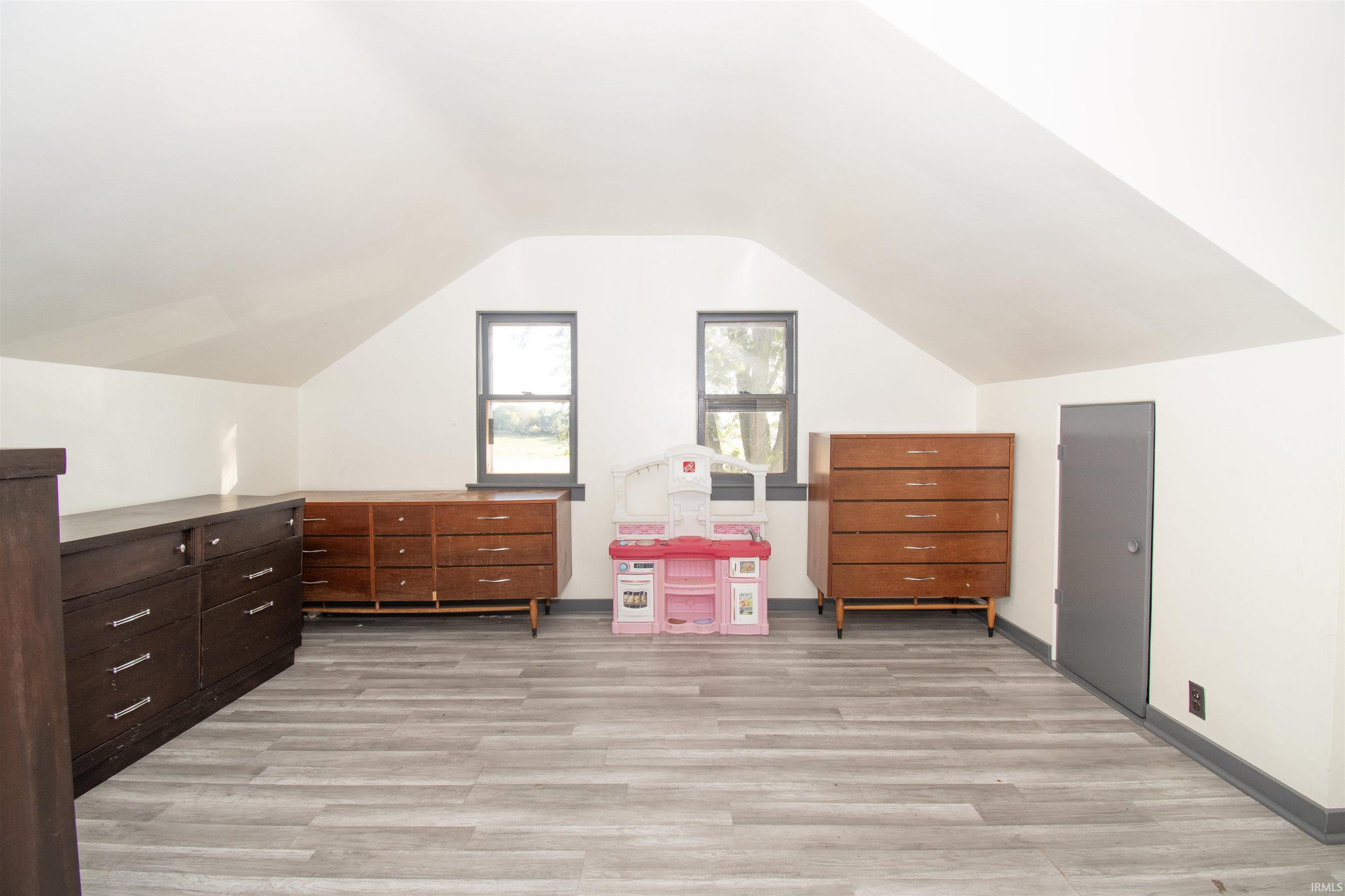 Additional living space with light wood finished floors and vaulted ceiling