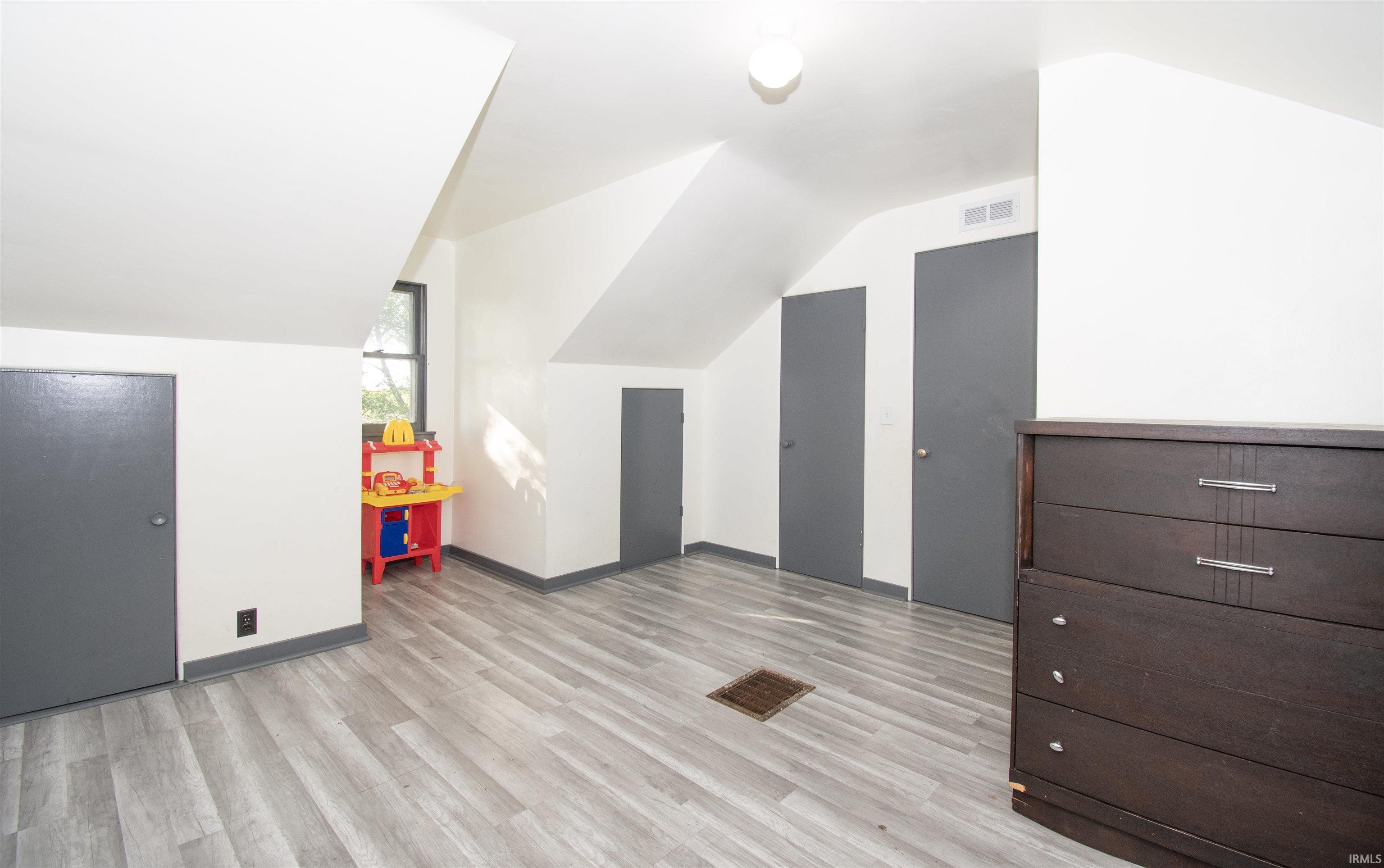 Bonus room featuring light wood-type flooring and lofted ceiling