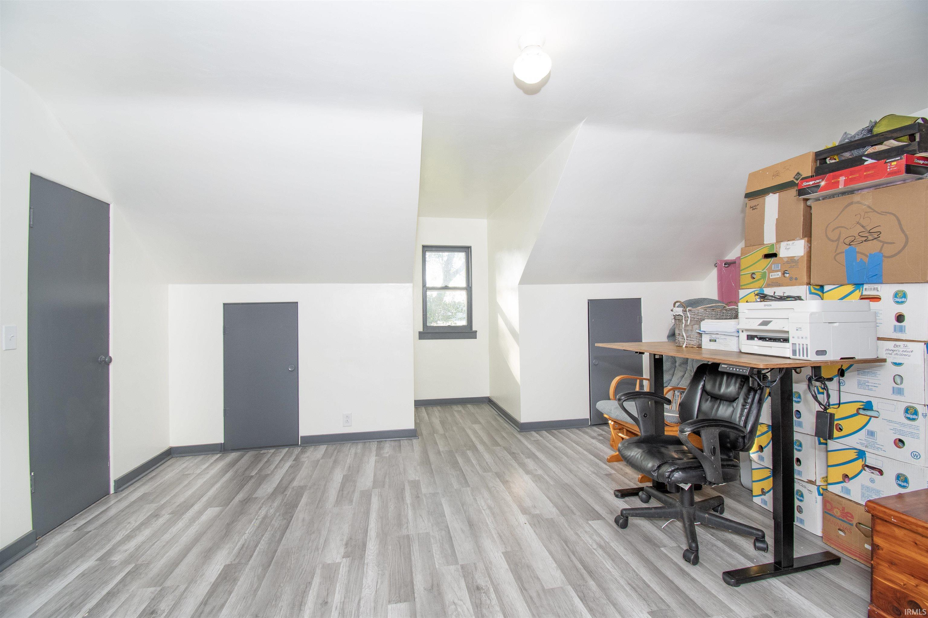 Office featuring vaulted ceiling and light wood-style flooring