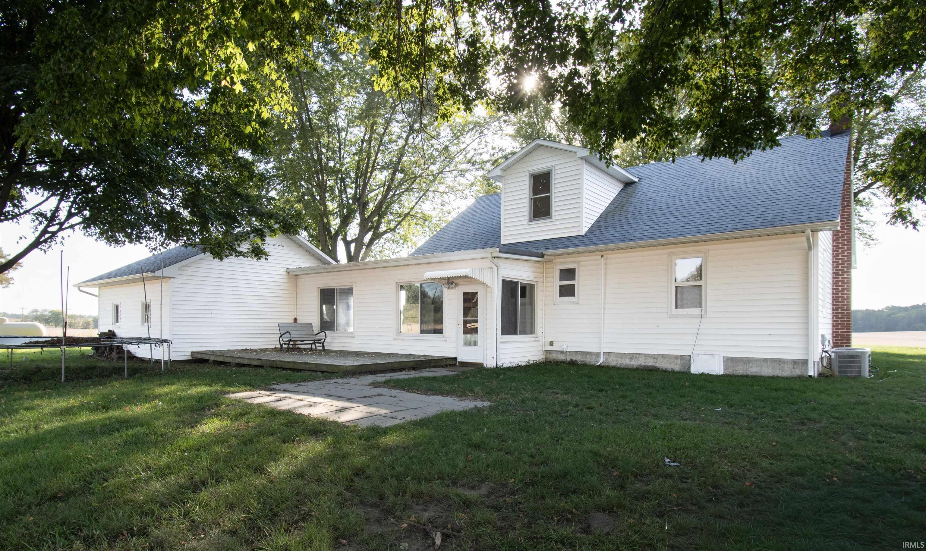 Rear view of property featuring a trampoline, a shingled roof, a lawn, and a deck