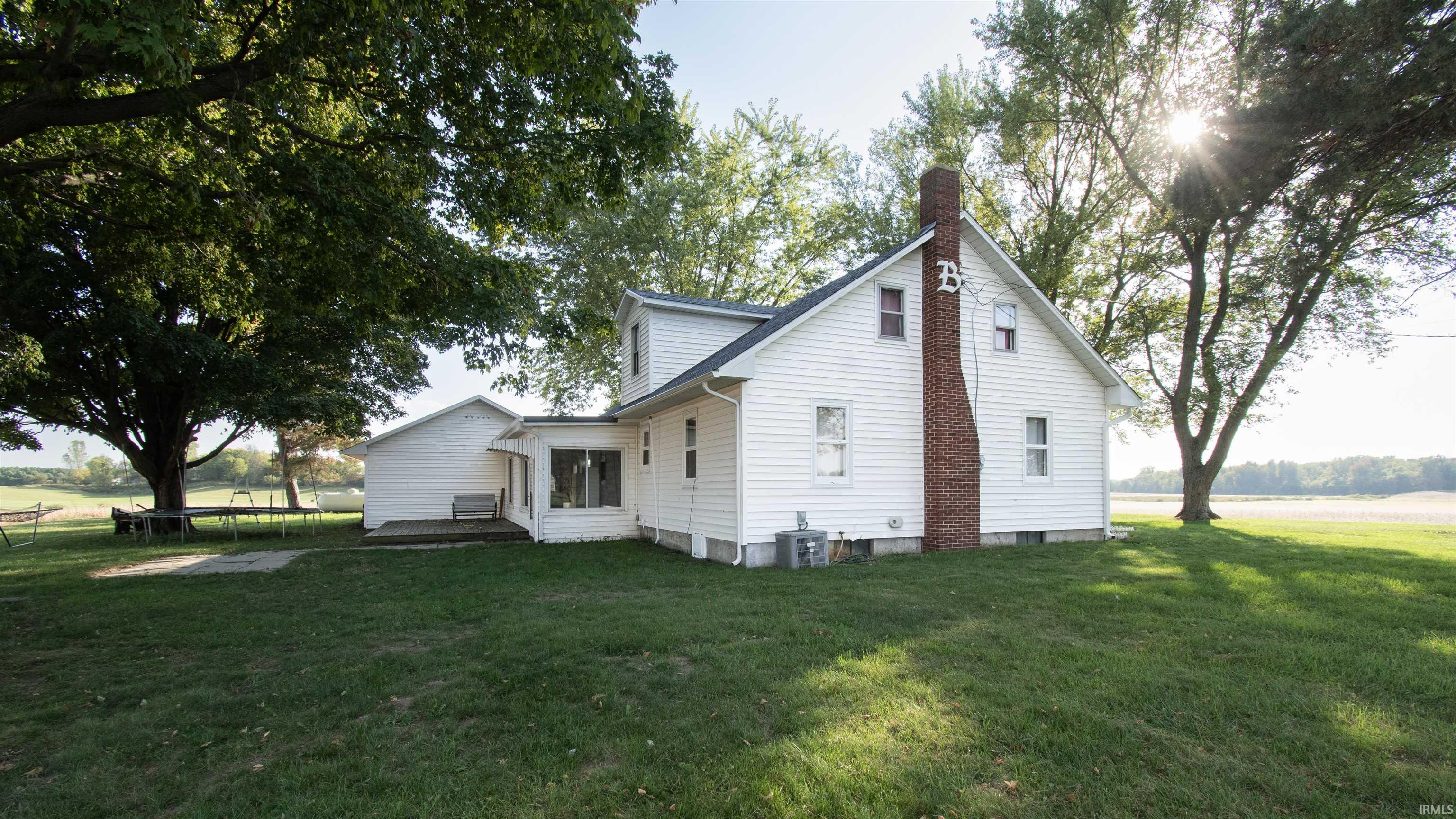 Rear view of property with a trampoline, a yard, and a chimney
