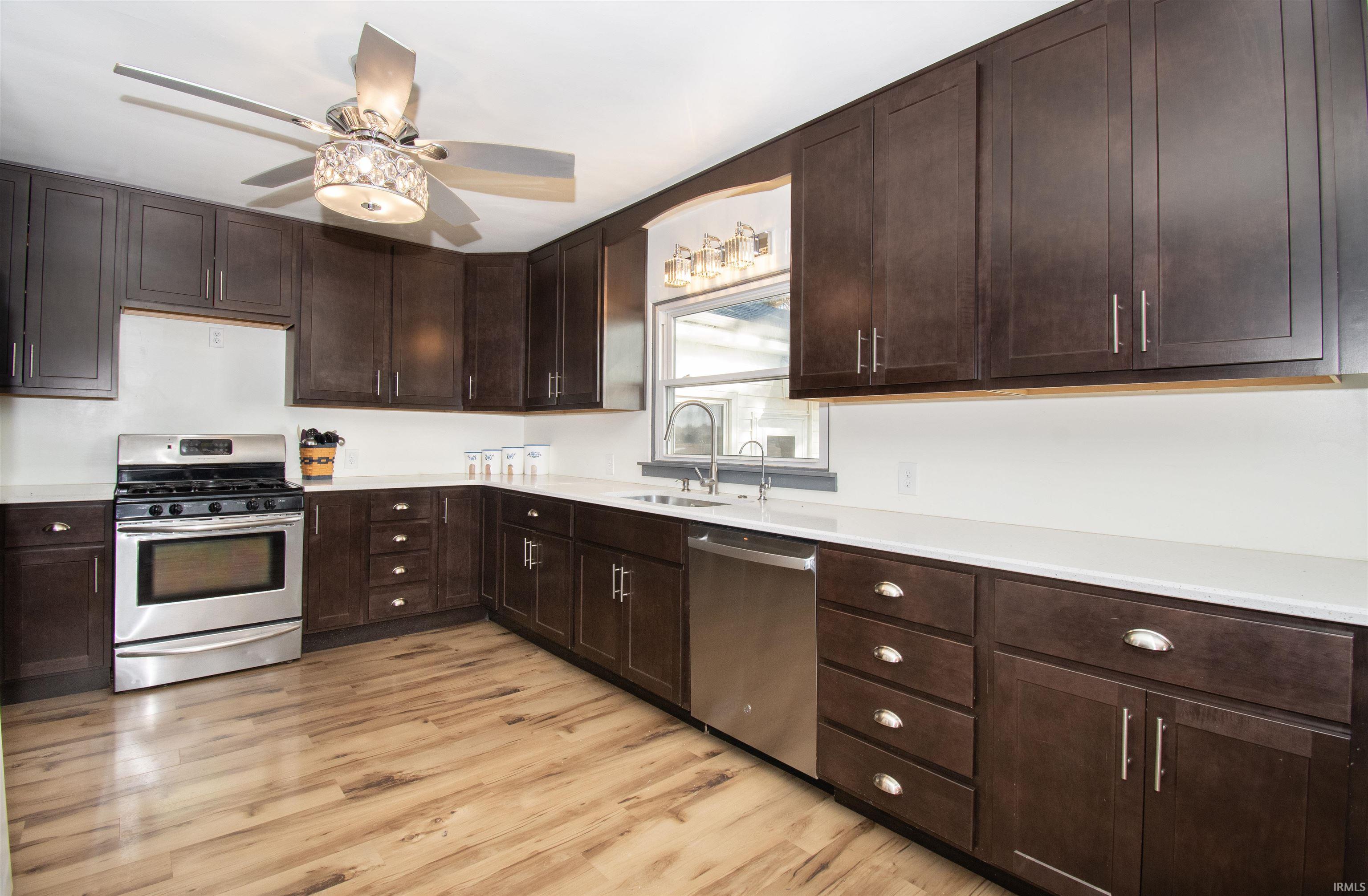 Kitchen featuring dark brown cabinets, appliances with stainless steel finishes, light wood finished floors, and a ceiling fan