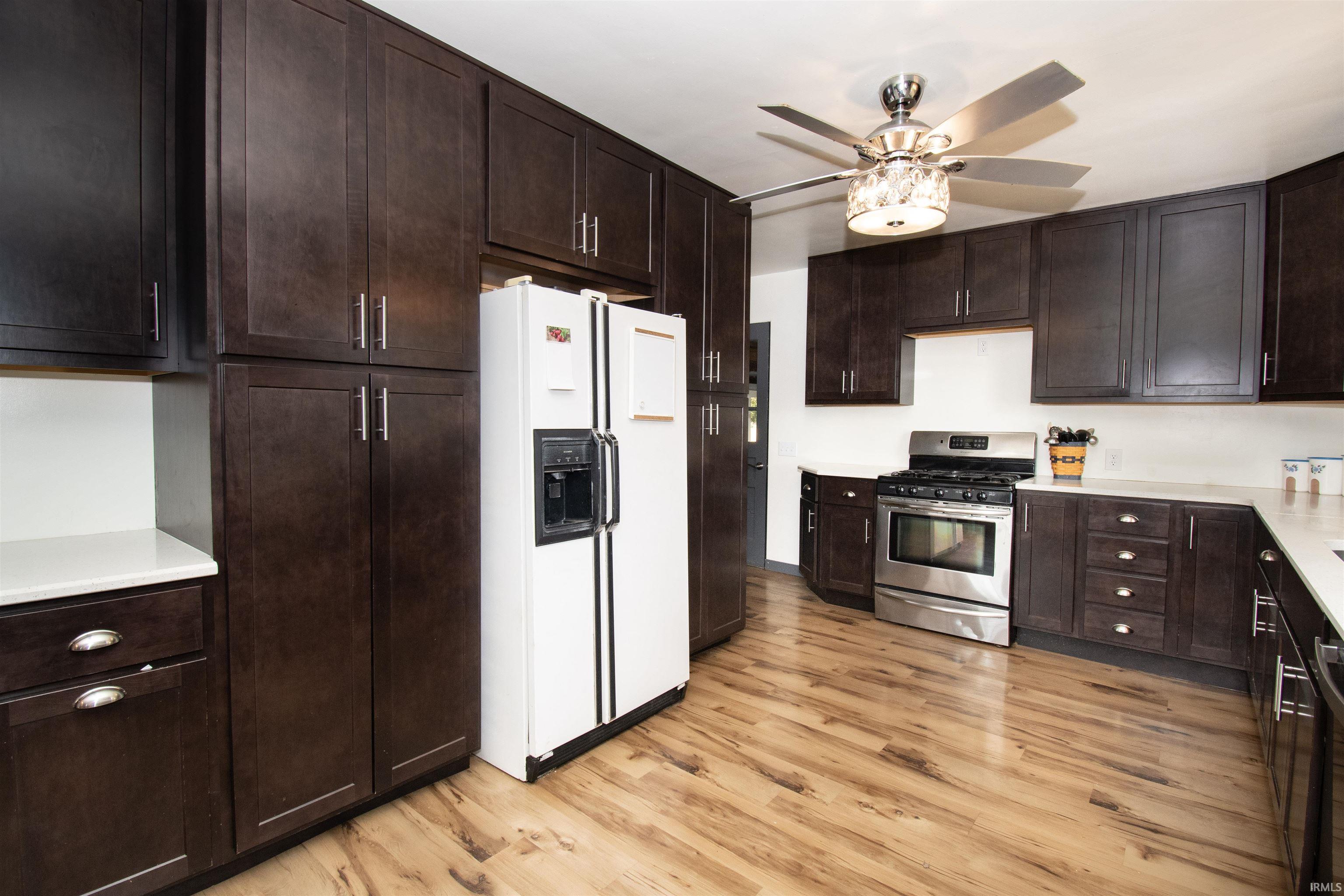 Kitchen featuring stainless steel appliances, dark brown cabinets, and light wood-type flooring
