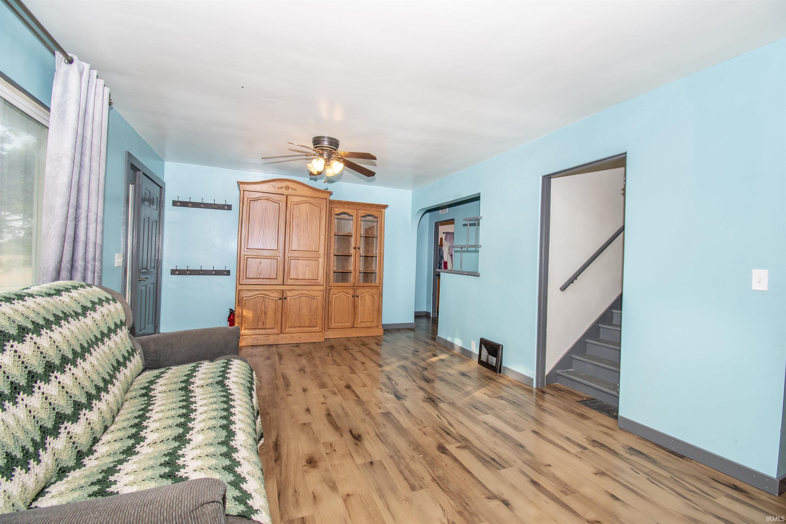 Living area featuring stairway, light wood-style flooring, and ceiling fan