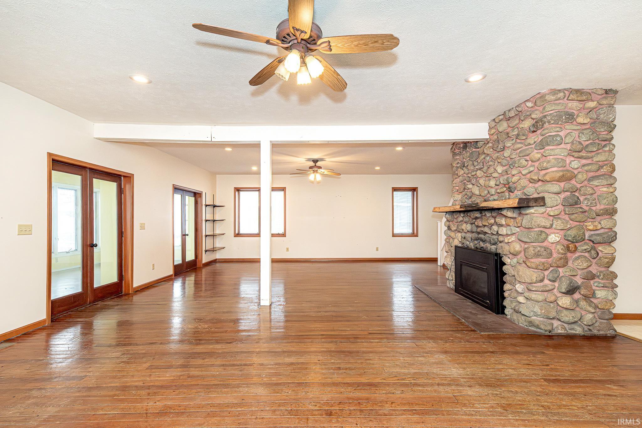 Unfurnished living room featuring a fireplace, light wood-style flooring, ceiling fan, recessed lighting, and french doors
