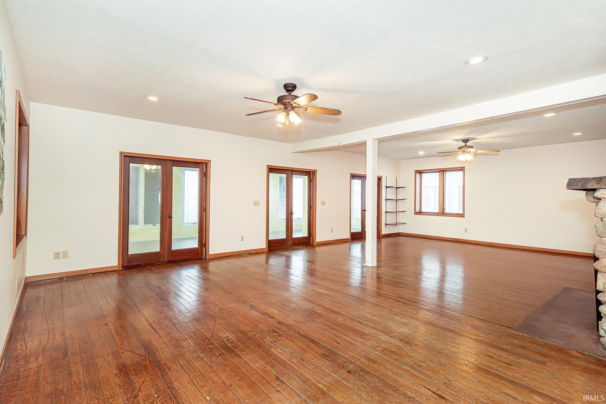 Unfurnished living room featuring hardwood / wood-style flooring, french doors, recessed lighting, and a ceiling fan
