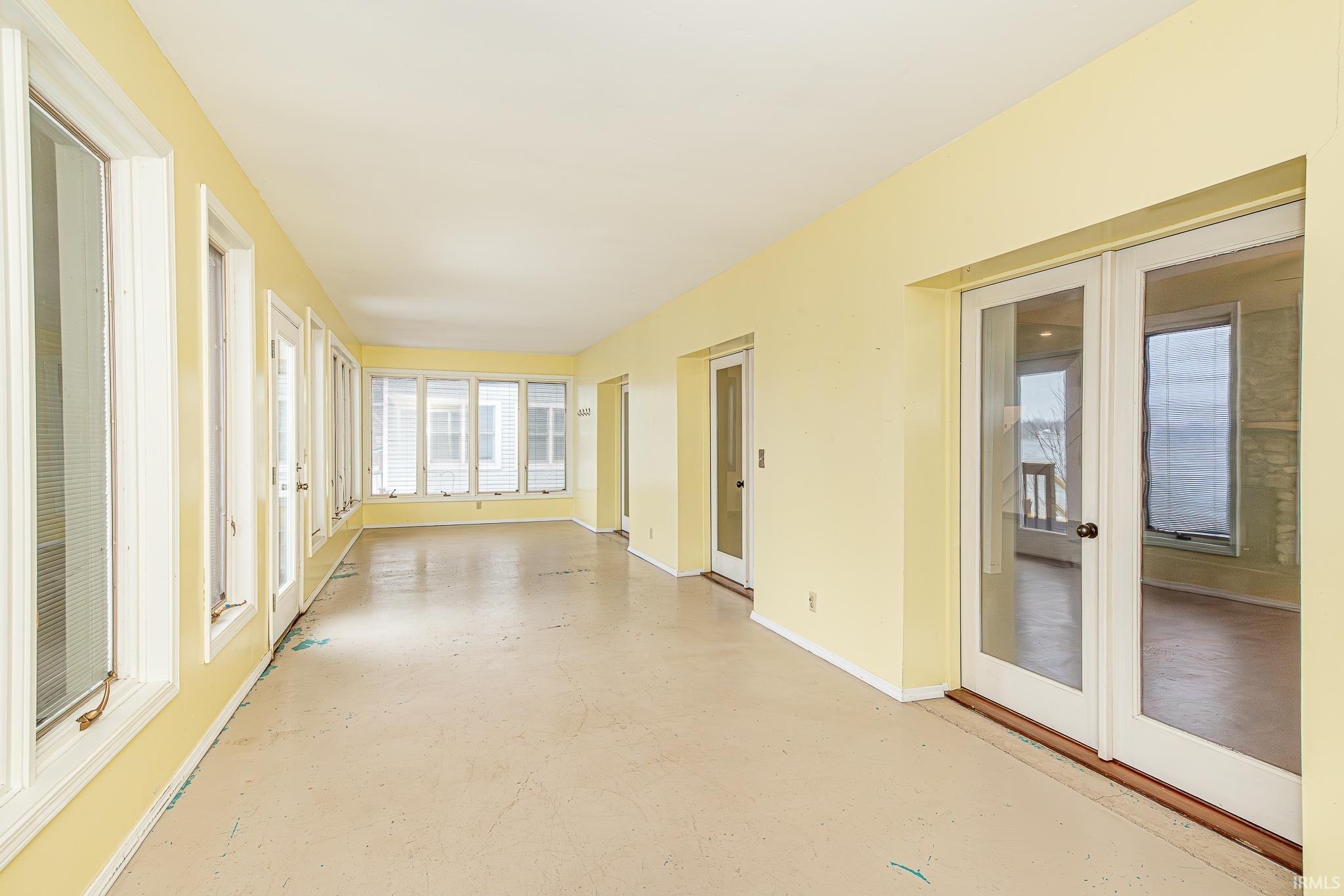 Unfurnished sunroom with french doors and concrete flooring
