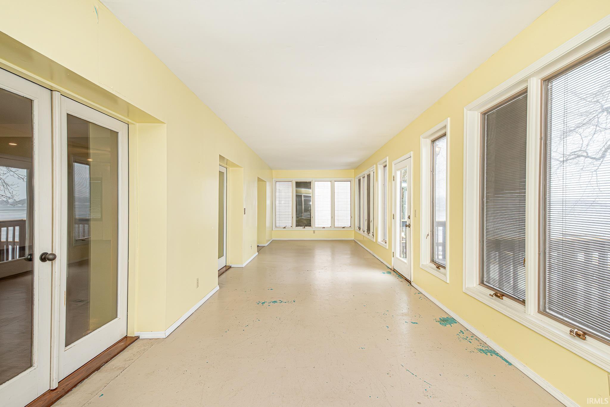 Unfurnished sunroom featuring french doors and concrete floors