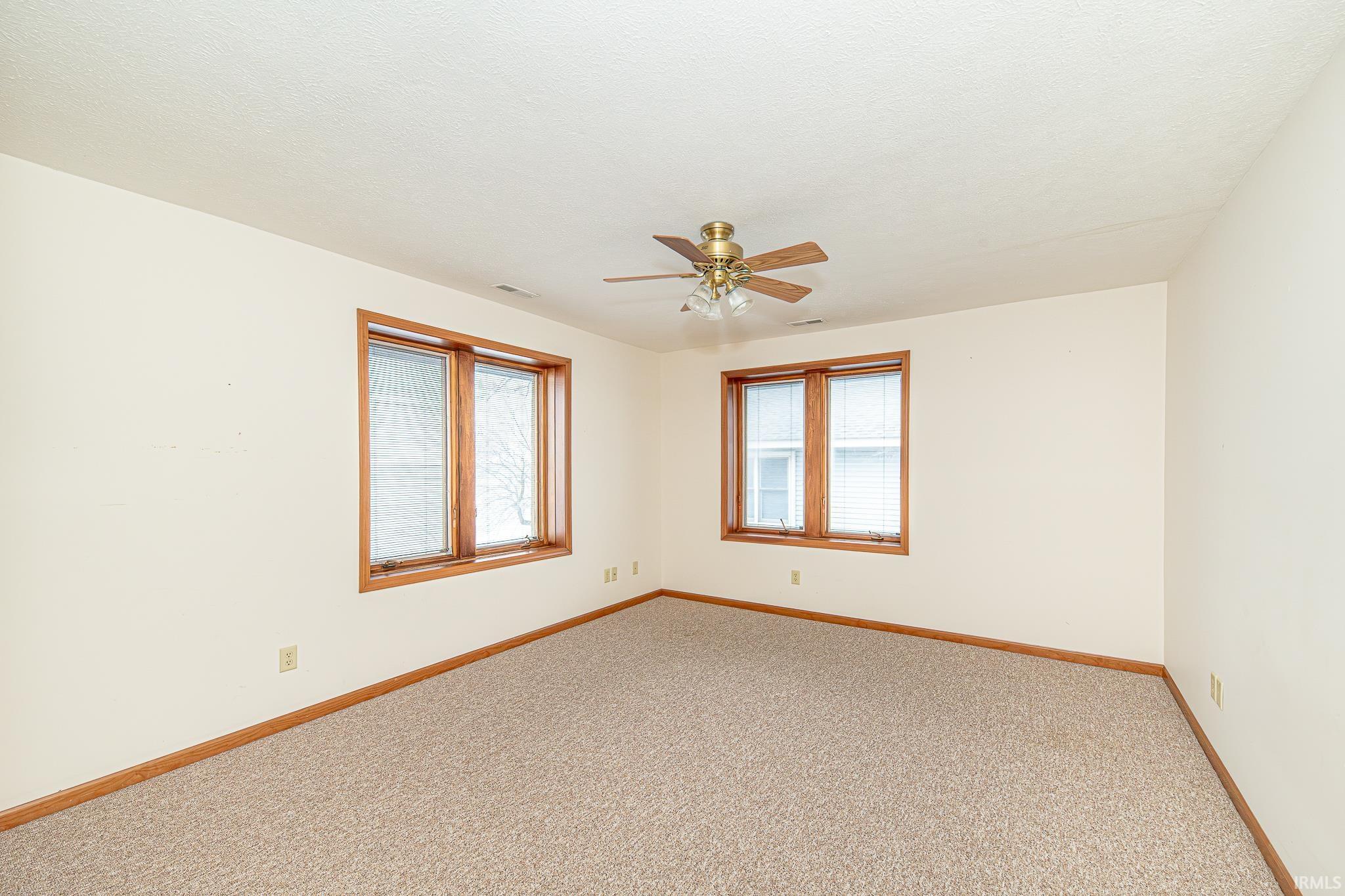 Spare room with carpet, ceiling fan, and a textured ceiling